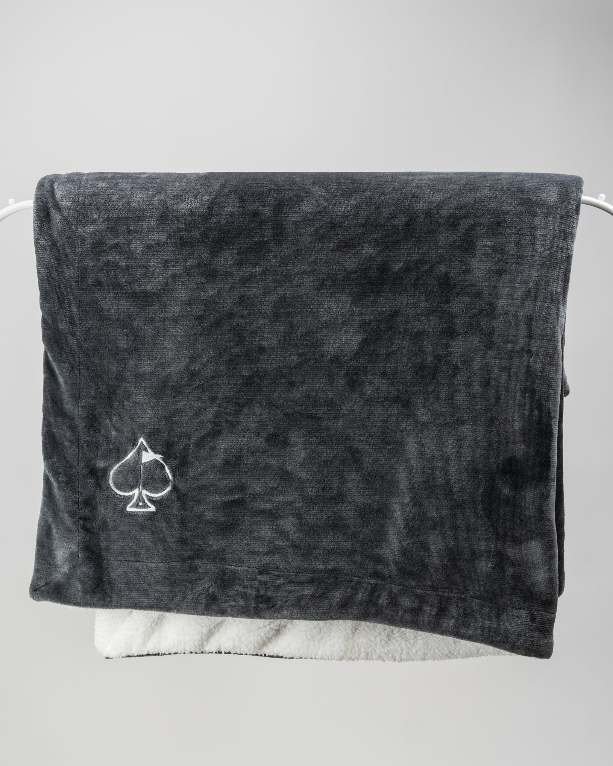 Dark gray Bogey Blanket displayed on a textured surface, showcasing its soft fleece material and elegant design.