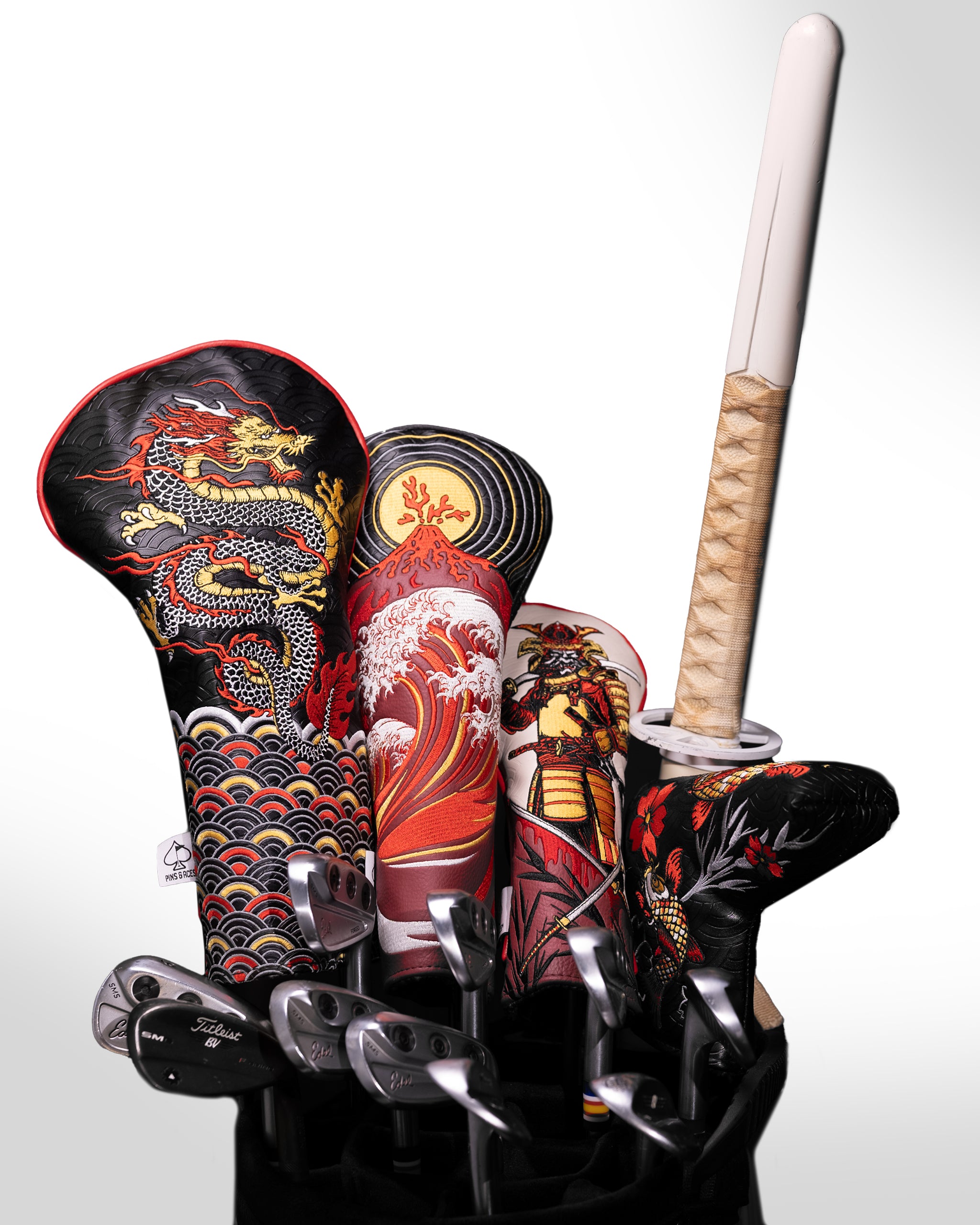 Colorful golf headcovers with bold Asian-inspired dragon, wave, and warrior designs, paired with a beige golf club grip.