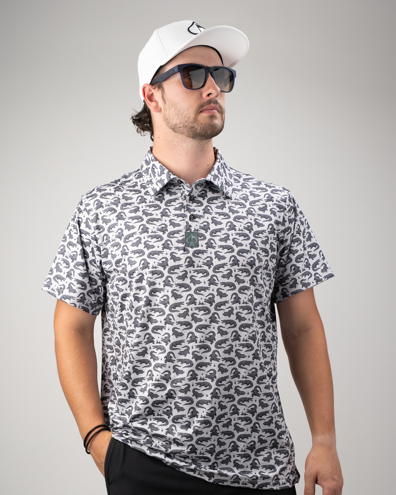 Men's golf shirt featuring a bold gator print in gray and black, paired with sunglasses and a white cap.