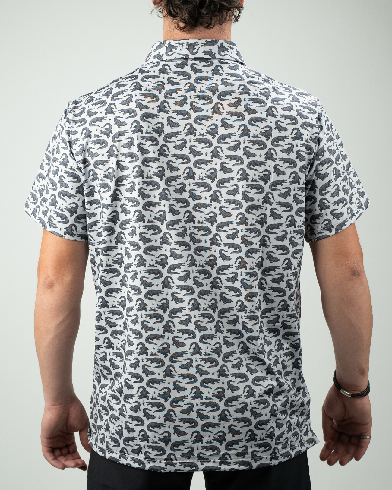 Men's short-sleeve golf shirt featuring a bold gator print in gray and black, viewed from the back.