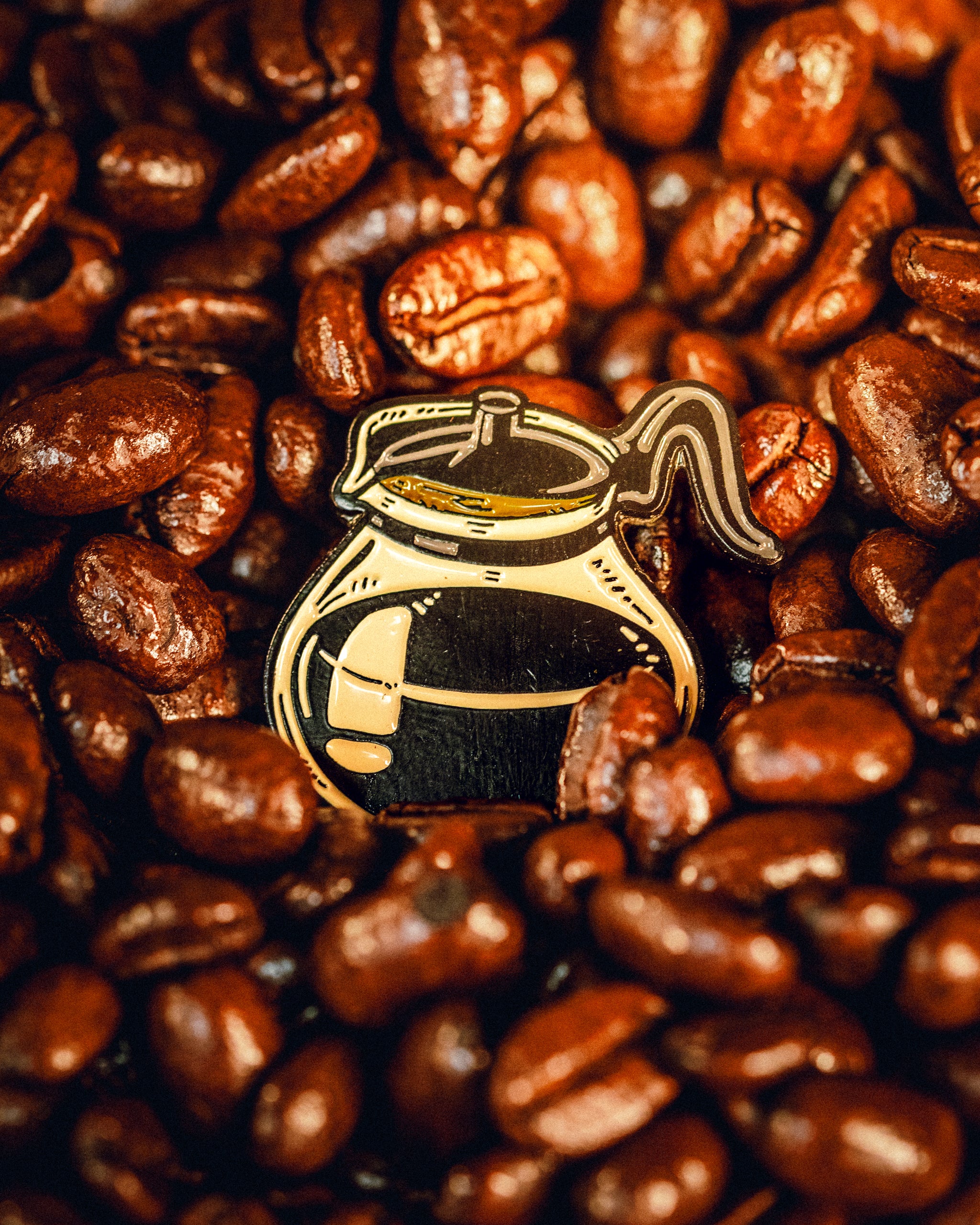 Coffee pot ball marker surrounded by roasted coffee beans, perfect for golfers who love coffee-themed accessories.