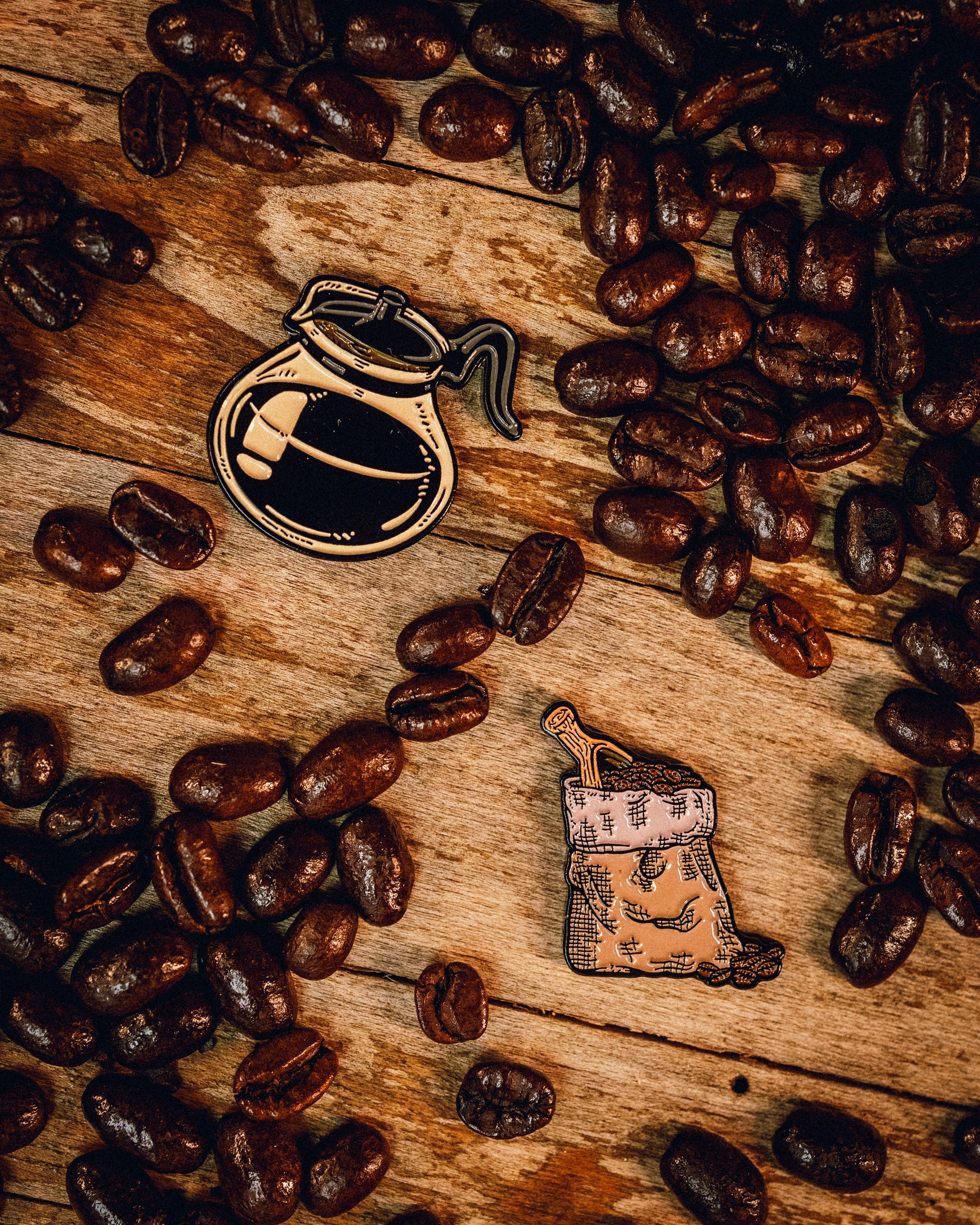 Coffee-themed ball markers featuring a coffee pot and a coffee sack, surrounded by coffee beans on a wooden surface.
