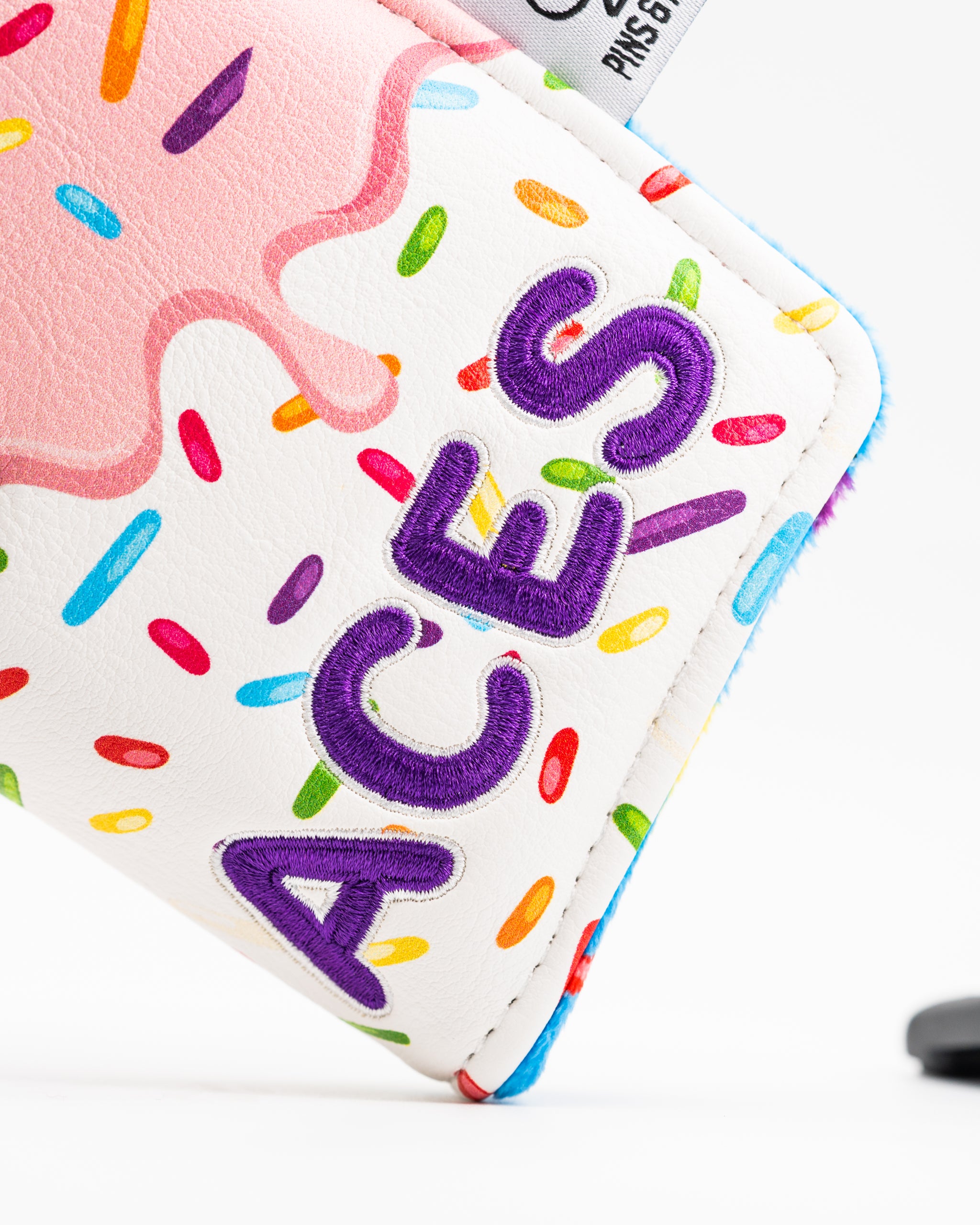 Colorful blade putter cover featuring a donut design with sprinkles and the word "ACES" in bold purple lettering.