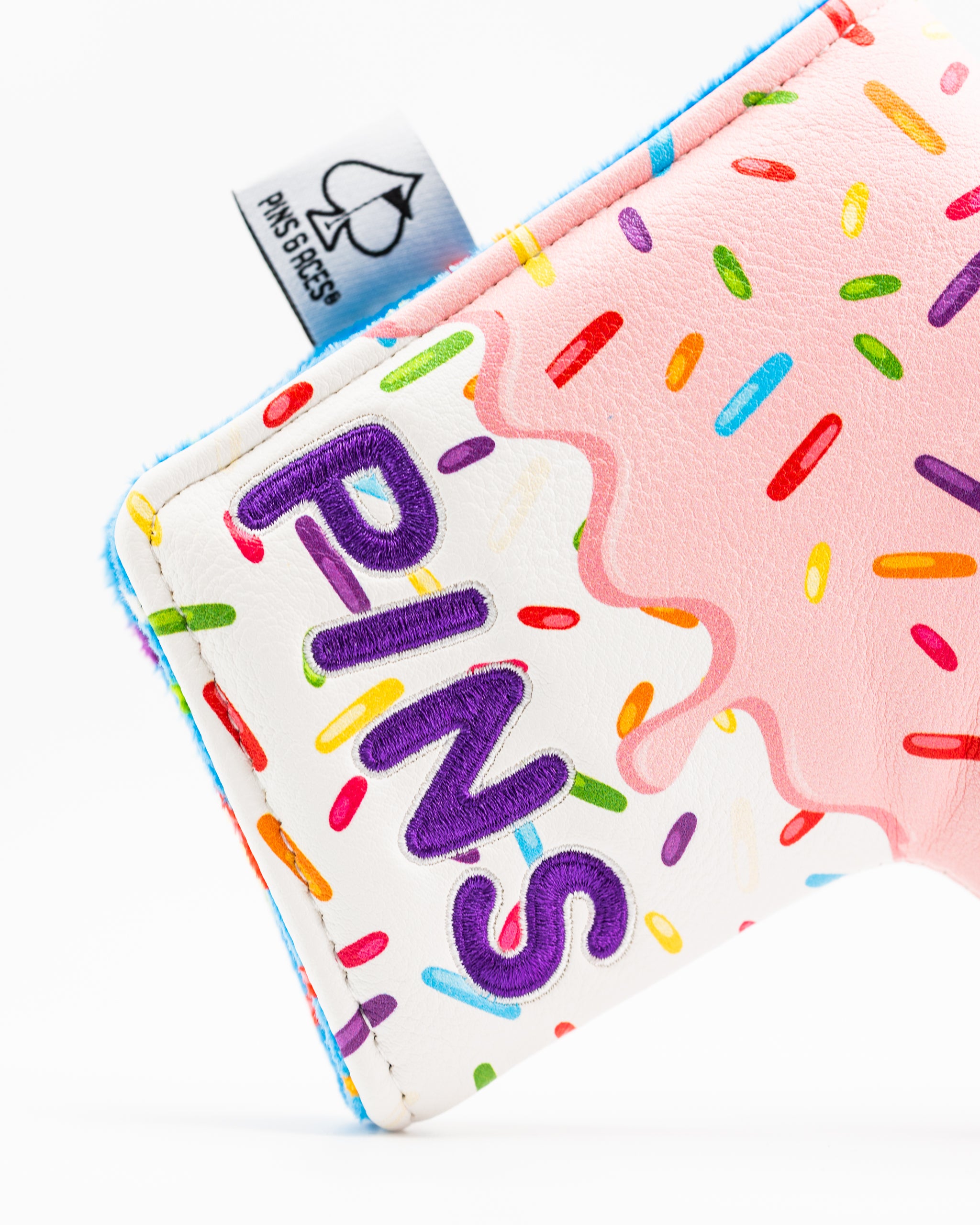 Colorful blade putter cover featuring a donut design with sprinkles and the word "PINS" prominently displayed.