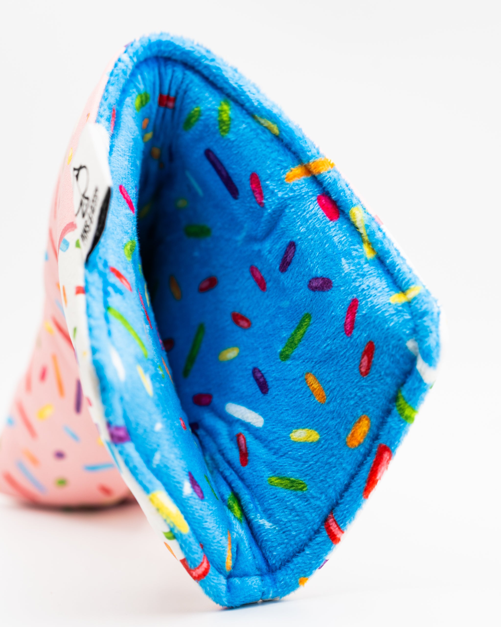 Colorful blade putter cover featuring a pink exterior with a sprinkle design and a soft blue interior.