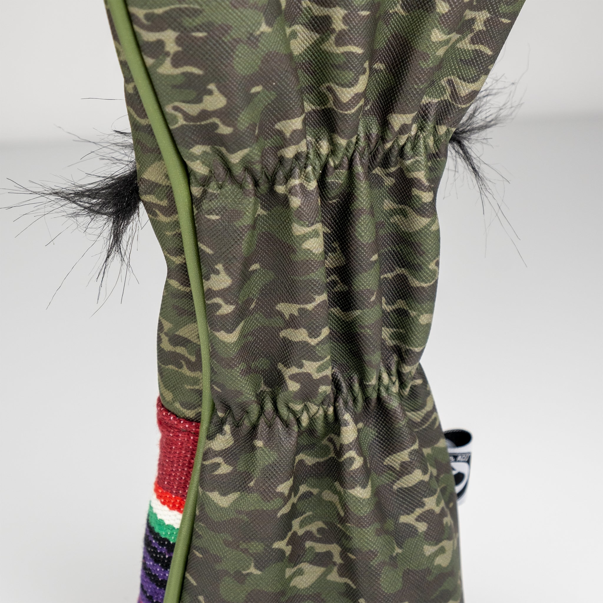 Camo-patterned golf headcover with black faux fur accents, featuring bold colors and unique design for standout style on t...