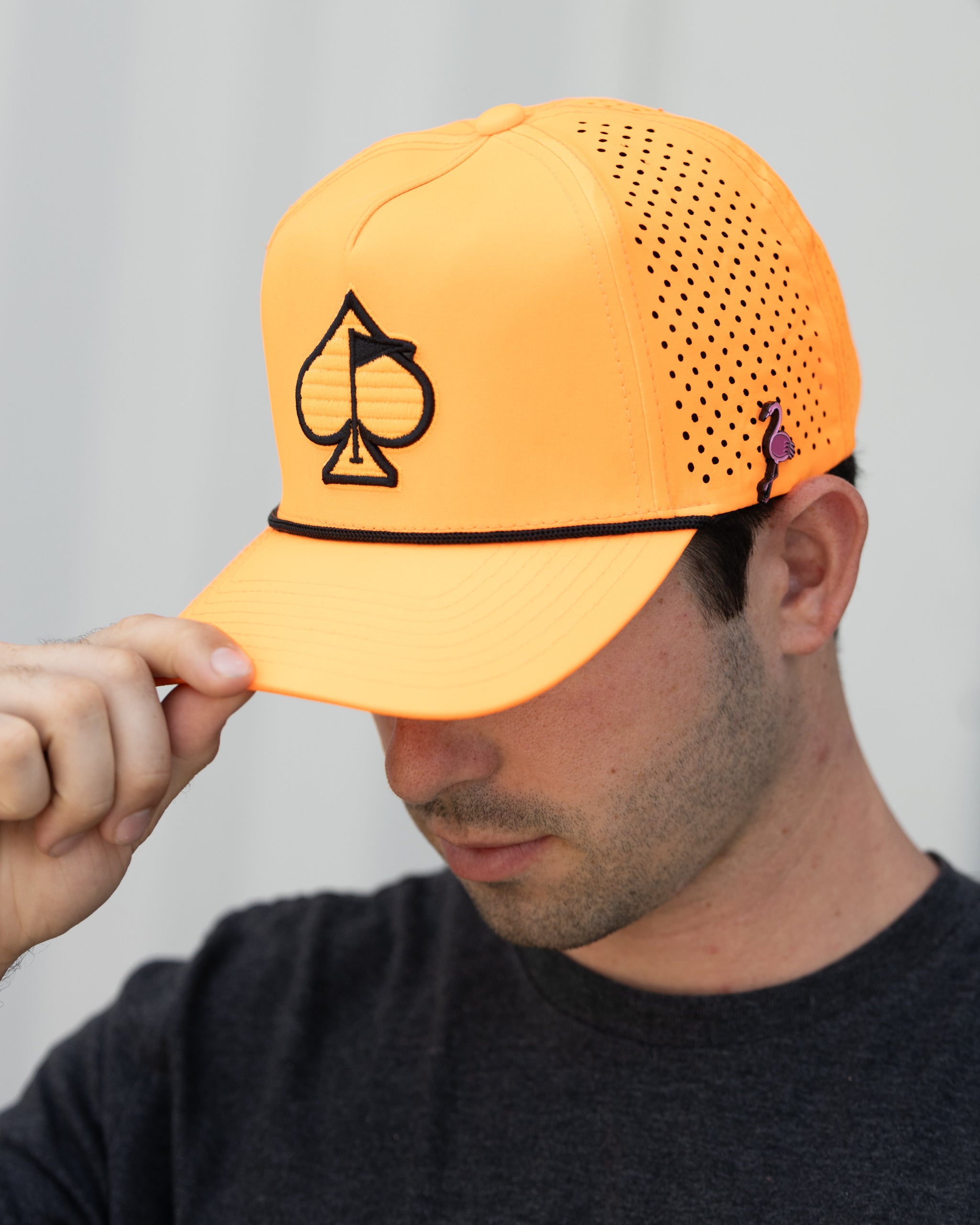 Highlighter orange perforated rope hat displayed outdoors, featuring a stylish design with a curved brim.