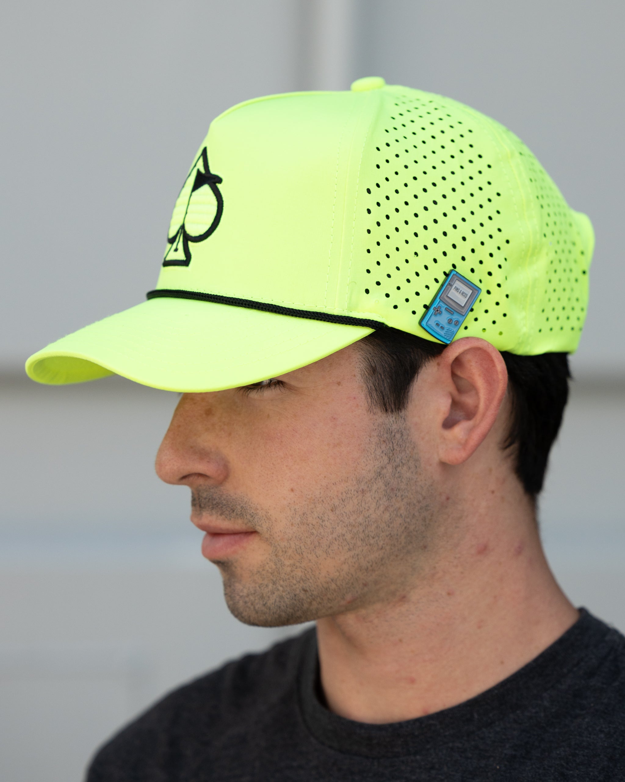 Perforated highlighter yellow rope hat displayed outdoors, featuring a wide brim and adjustable chin strap.