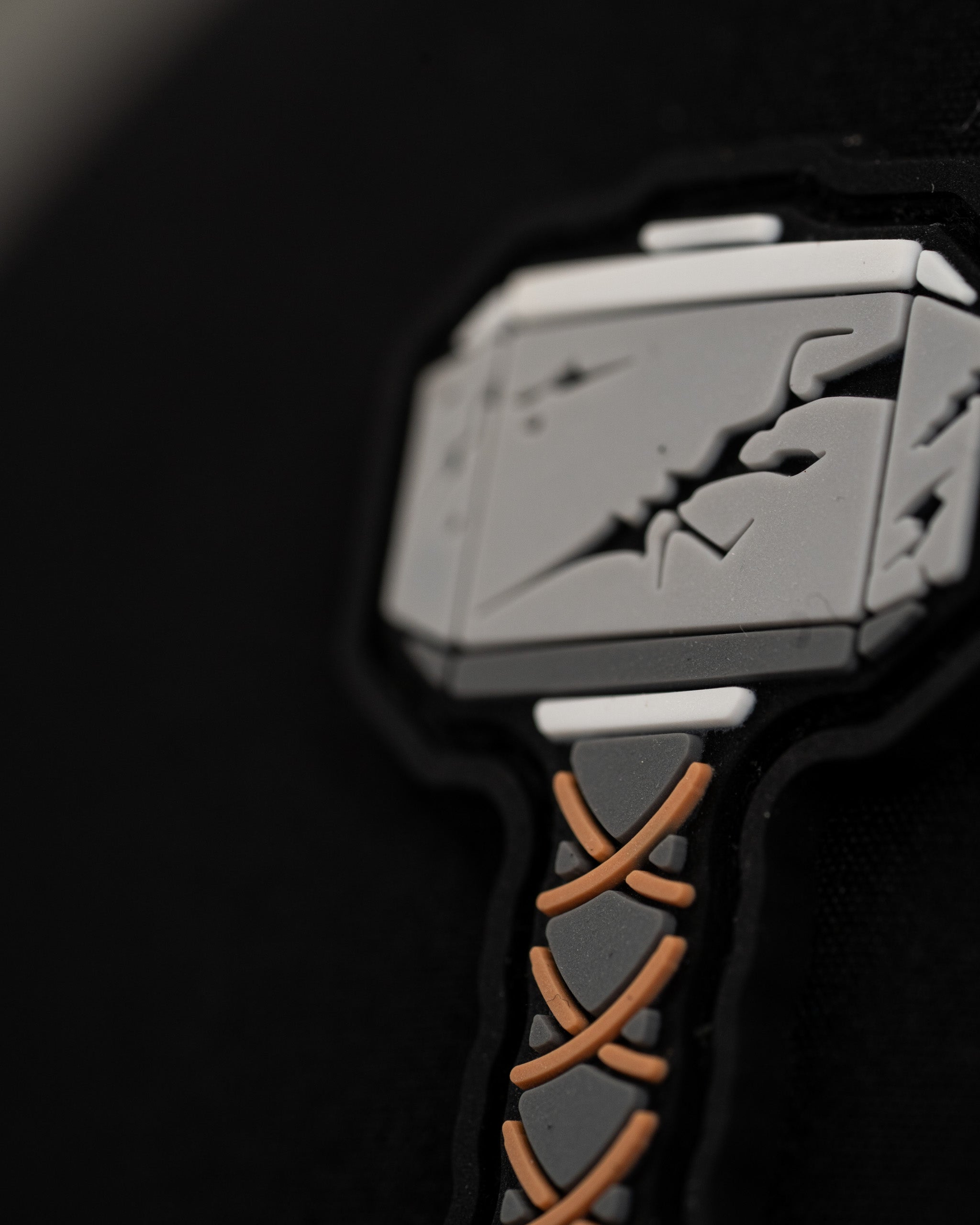 Close-up of a black perforated rope hat featuring a detailed Thor's Hammer logo in gray and brown.