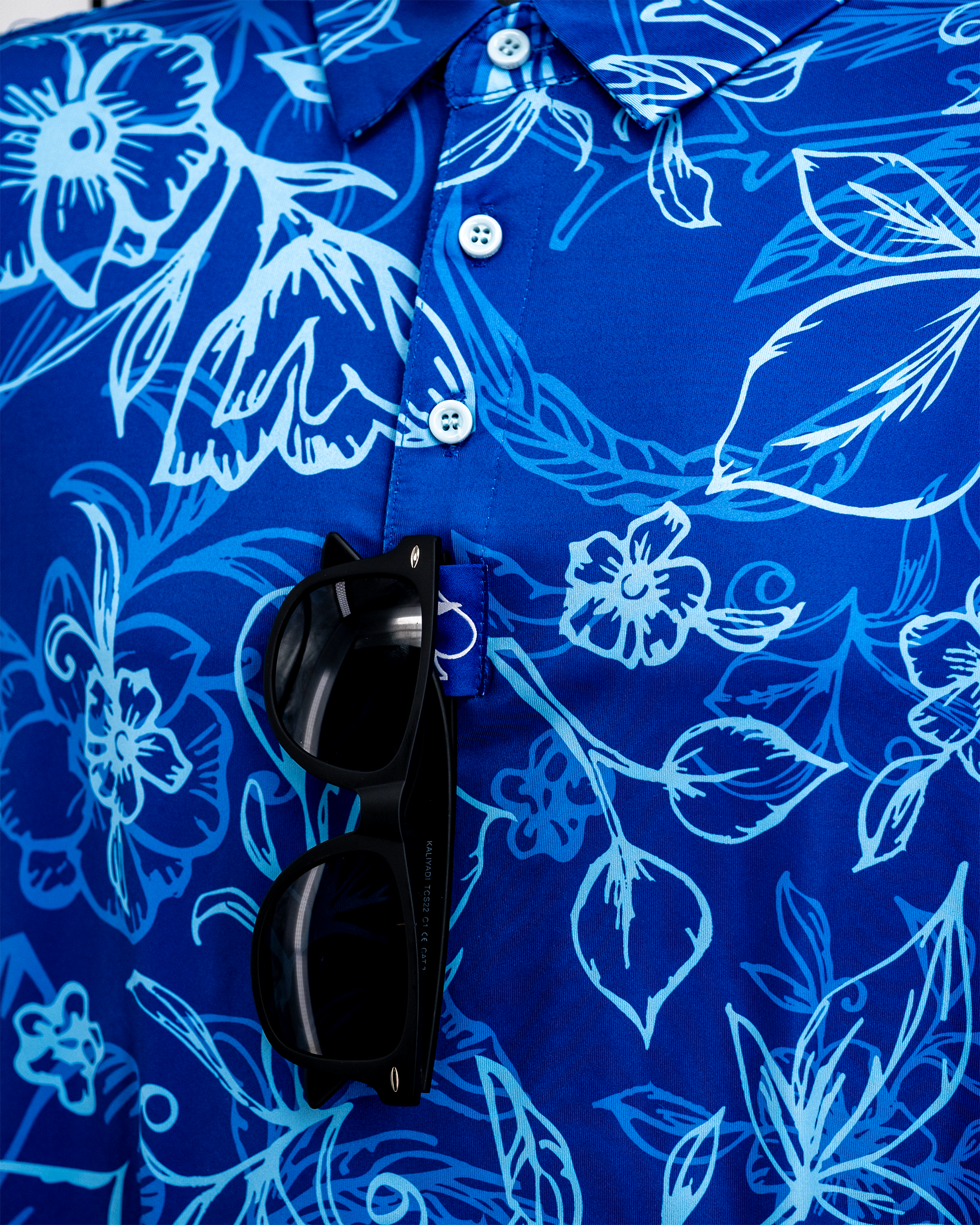 Cabo Ocean hanging polo shirt in vibrant blue with a relaxed fit and short sleeves, displayed on a wooden hanger against a neutral background.