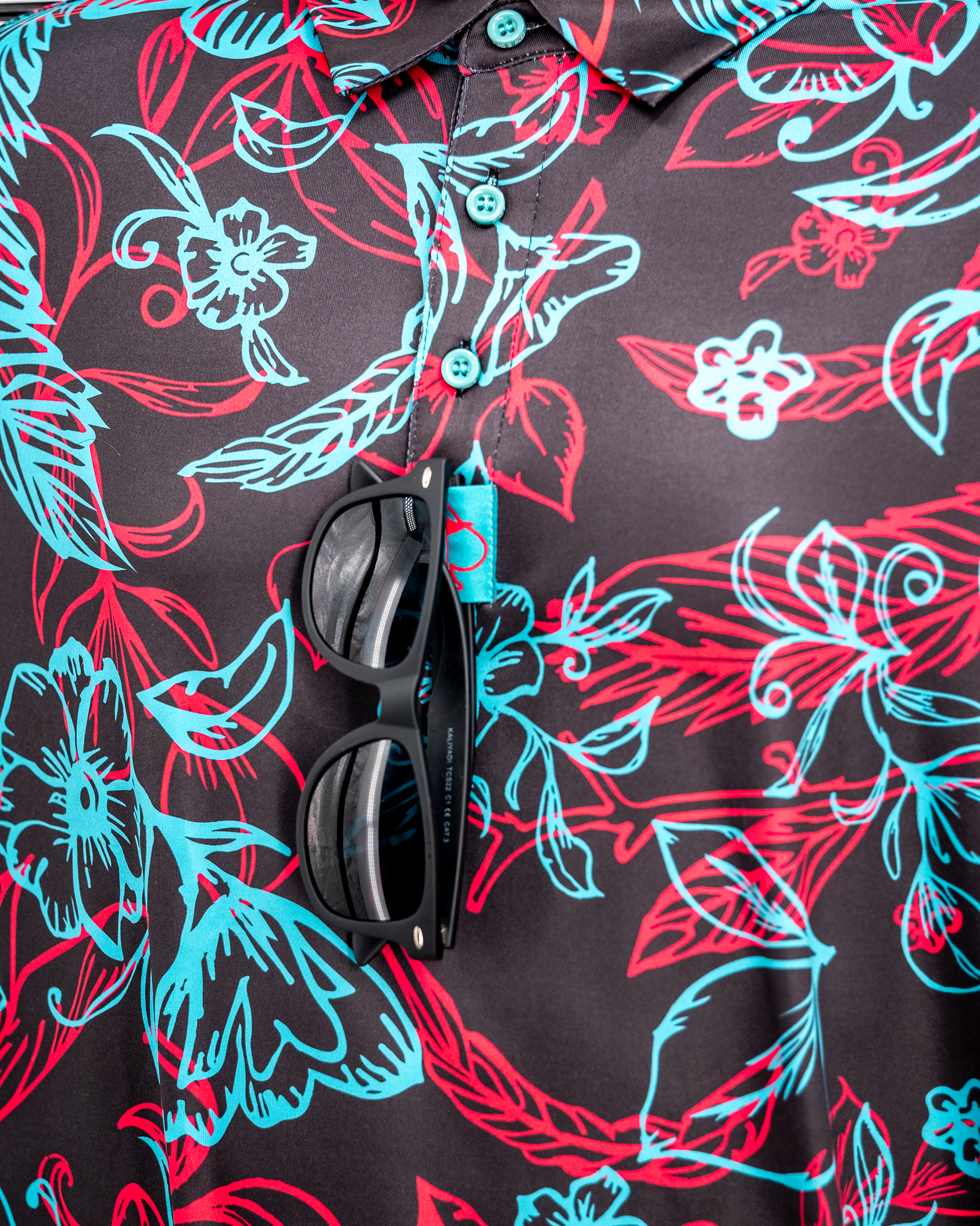 Cabo Electric logo on a vibrant background with various colored hanging polo shirts.