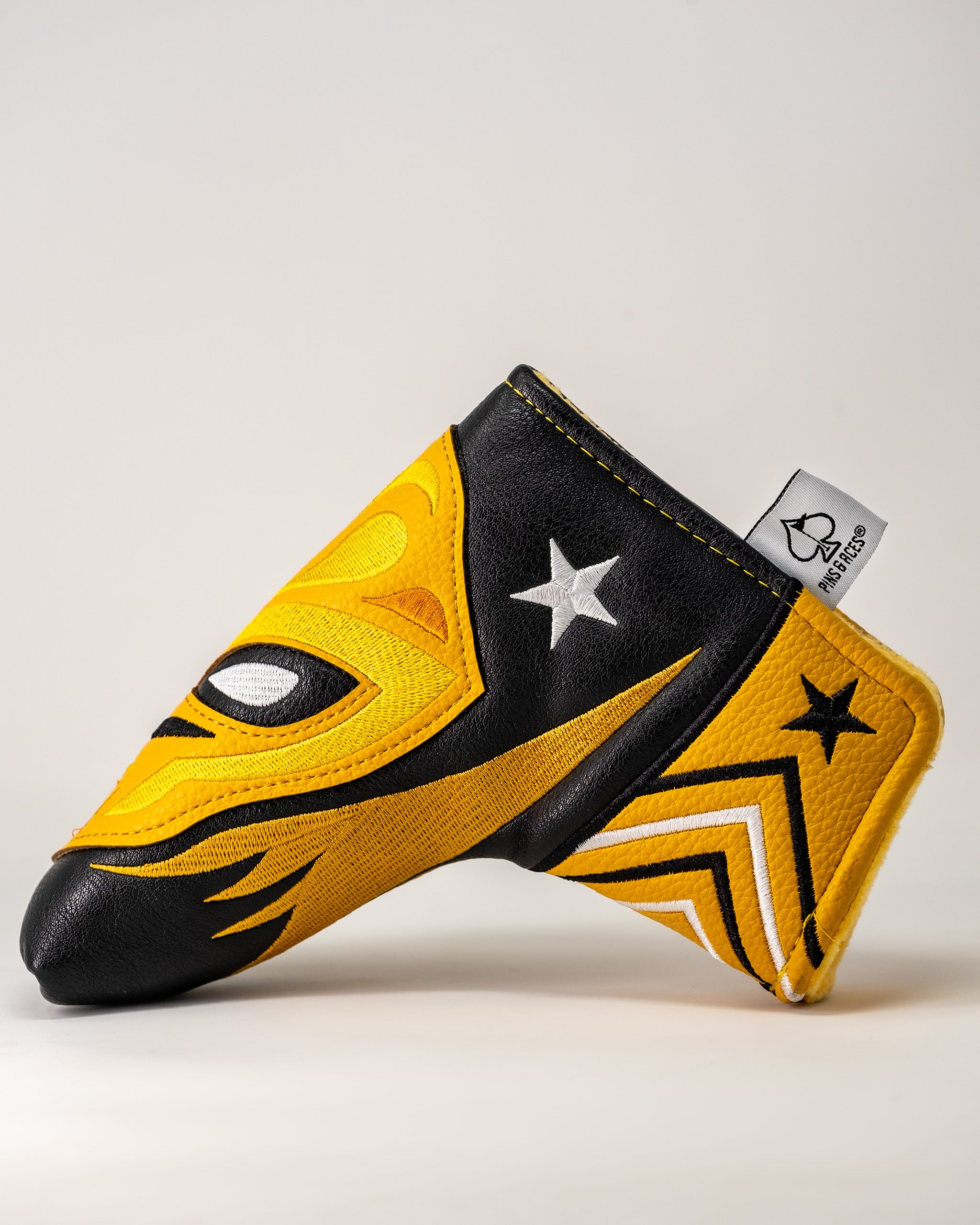 Lucha Libre mask-inspired Blade Putter Cover with yellow, black, and white star design, made of textured material.