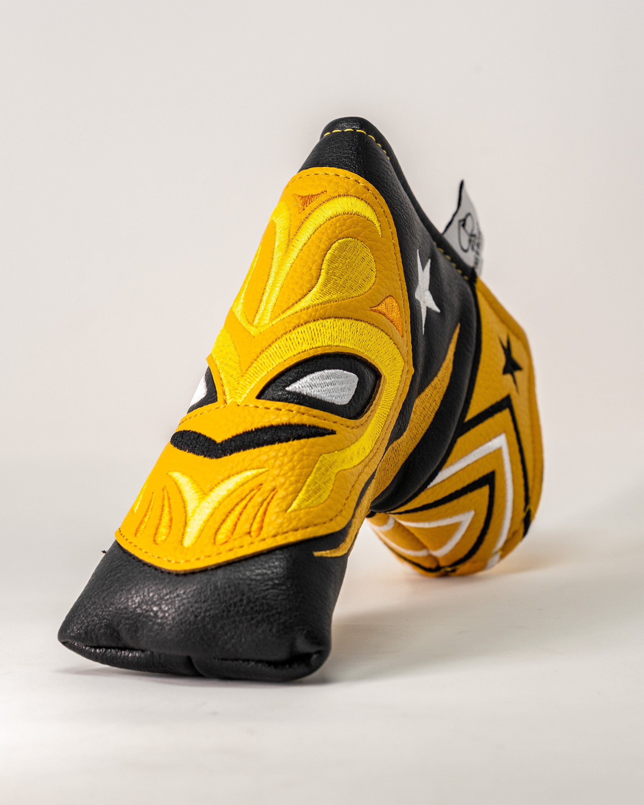 Lucha Libre mask-inspired Blade Putter Cover with vibrant yellow, black, and white embroidery resembling a wrestling mask.