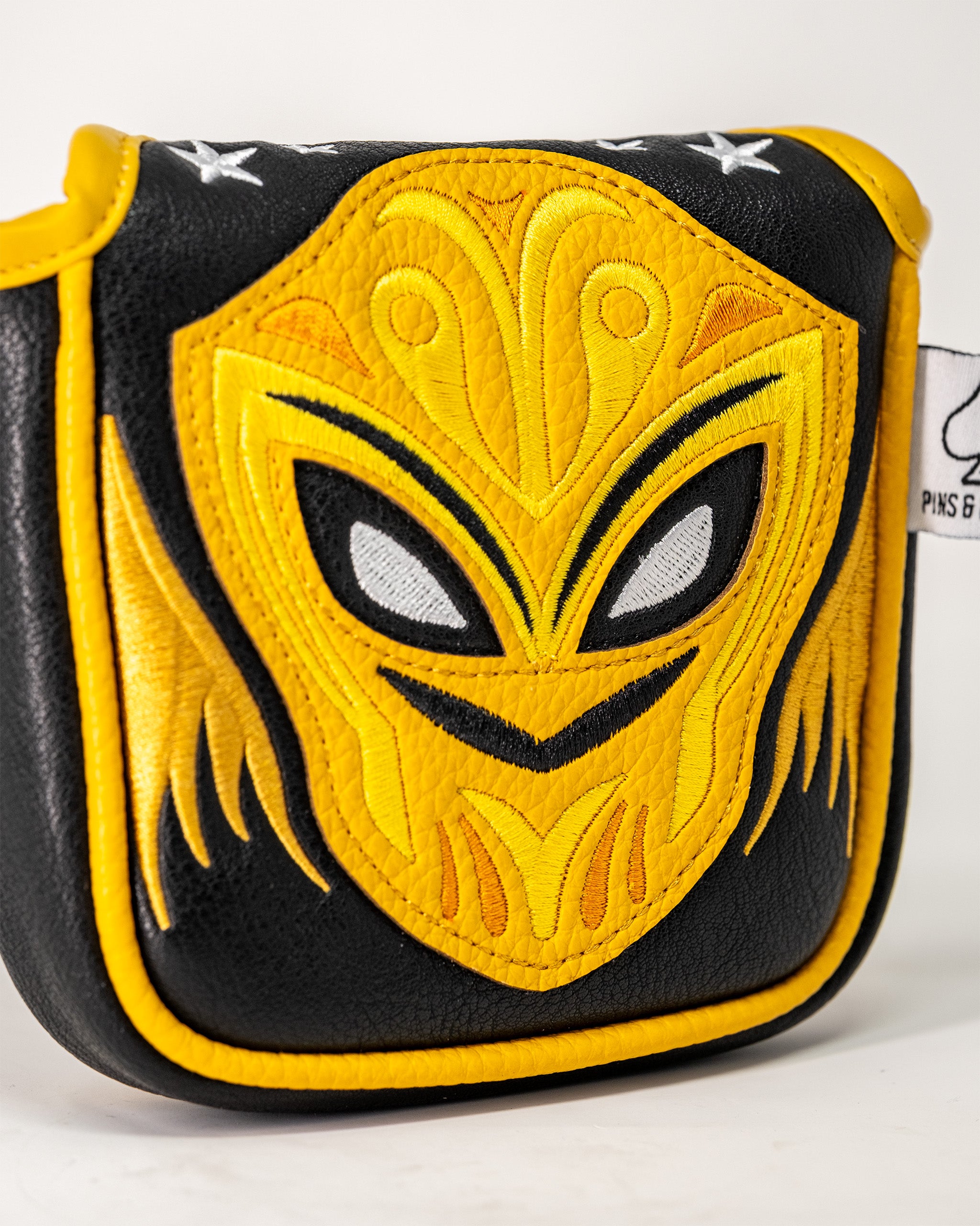 Lucha Libre mask-themed mallet putter cover in black and yellow with embroidered mask design, protecting golf clubs.