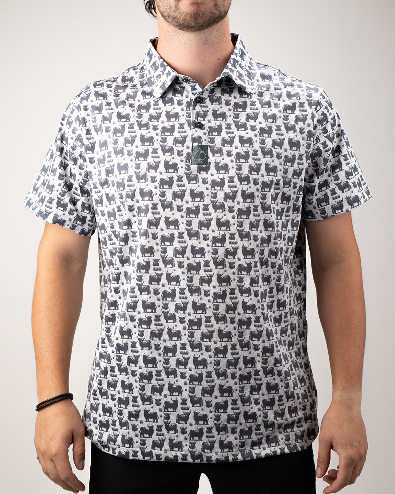 Highland cow patterned golf polo shirt worn by a man, featuring a playful design in shades of gray and black.