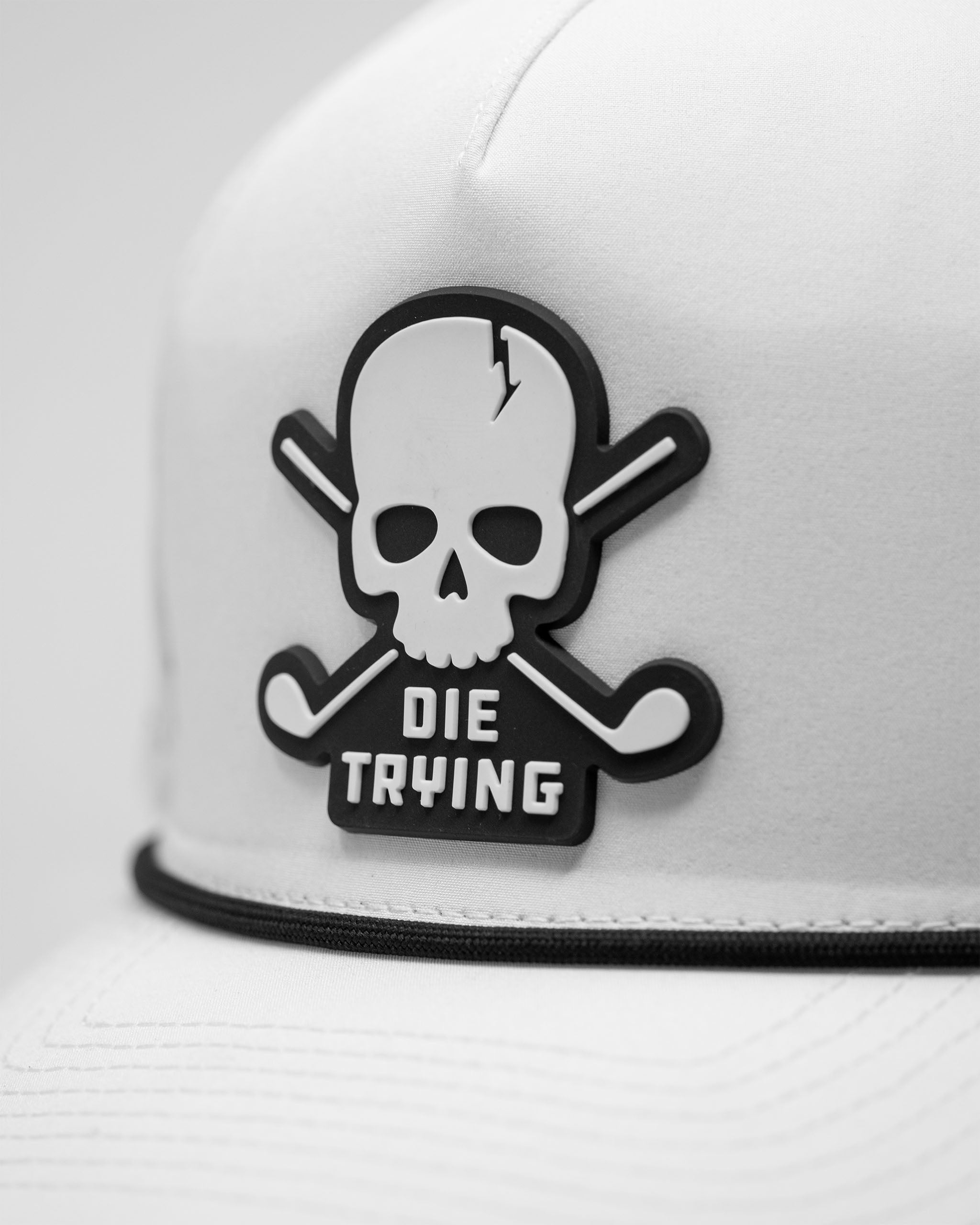 White perforated rope hat with a black skull and crossed golf clubs patch that says "Die Trying" on the front.