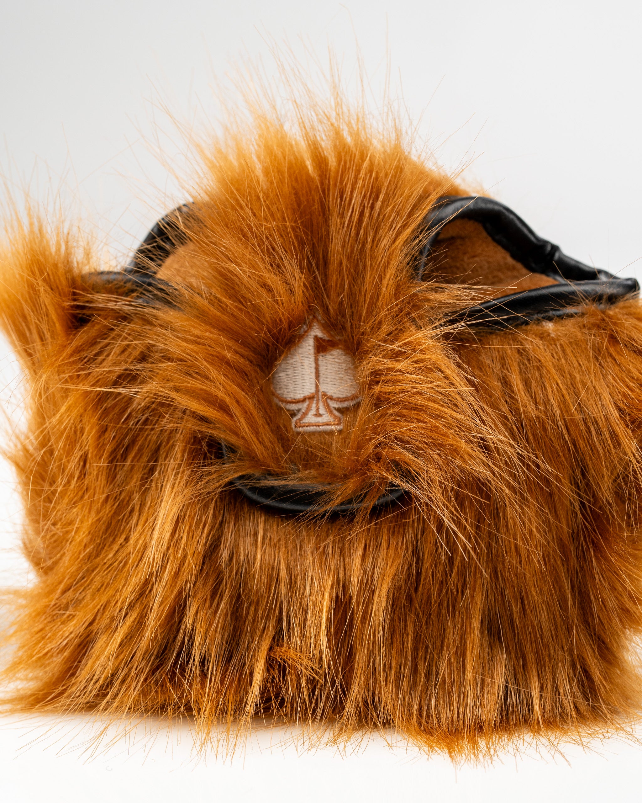 Highland cow mallet putter cover with a fluffy orange exterior and a stitched logo, designed for unique golf style.