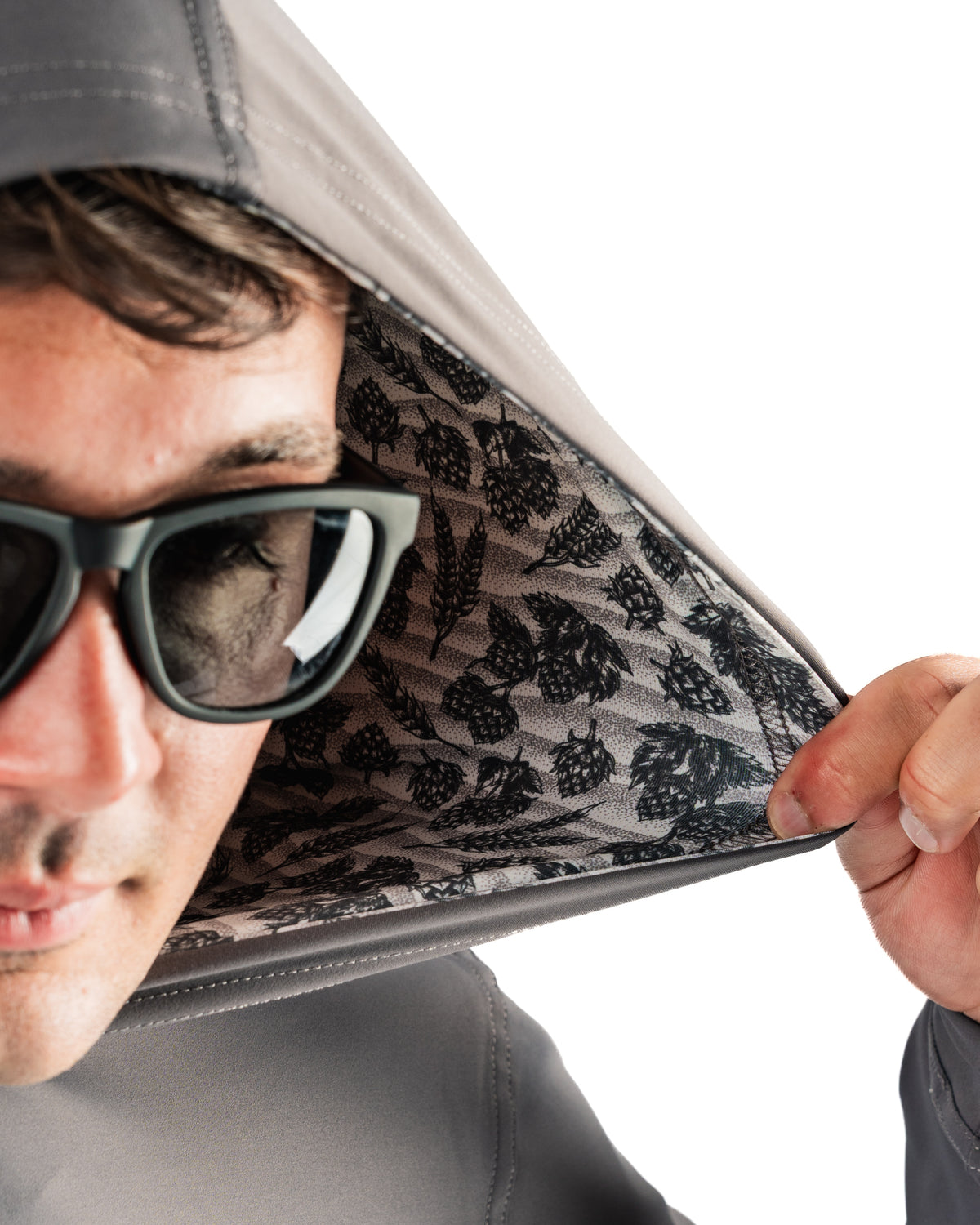 Performance golf hoodie in gray with a unique hops and barley pattern inside the hood, worn by a man in sunglasses.