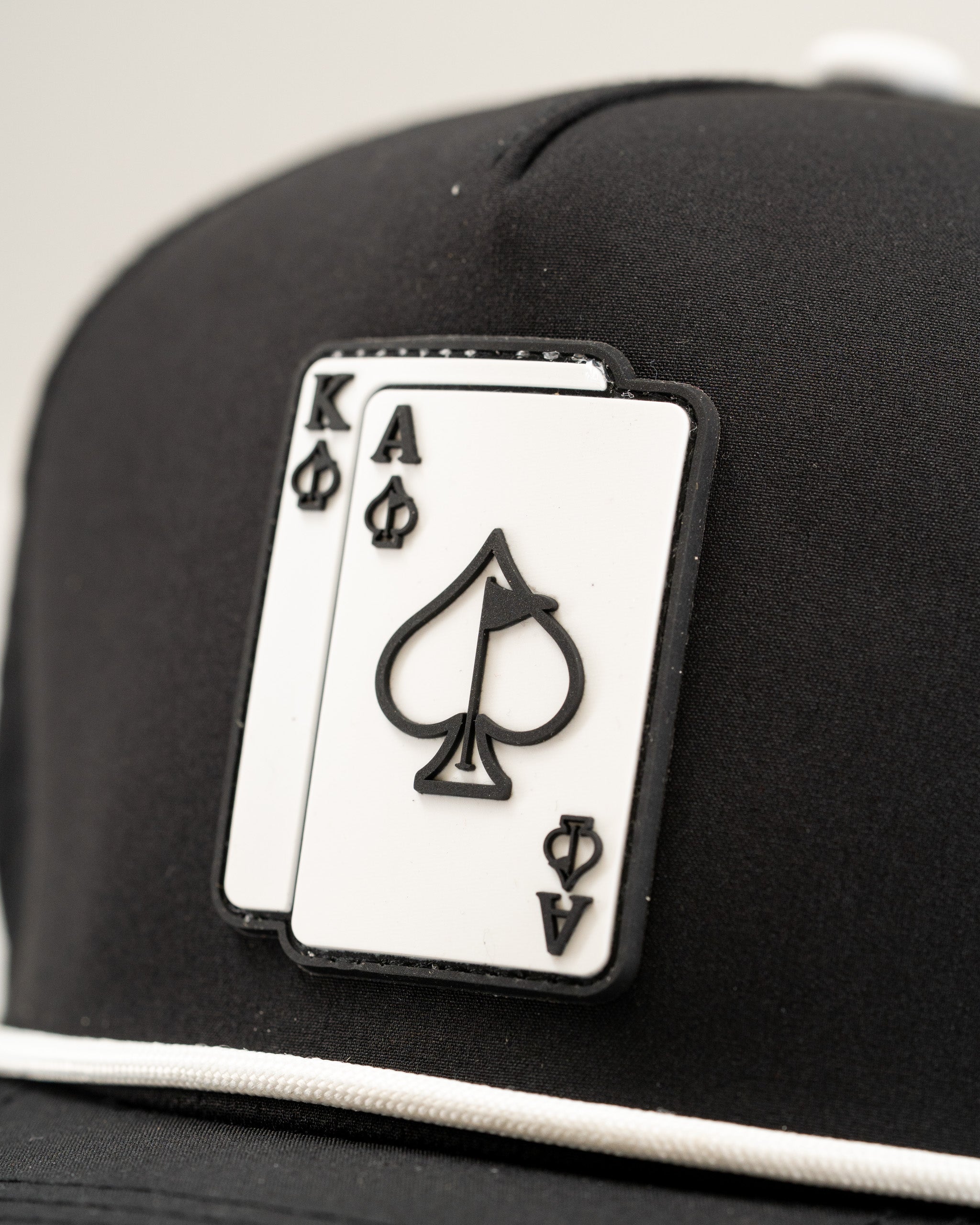 Black perforated rope hat featuring a bold Ace and King playing card design on the front. Ideal for stylish golfers.