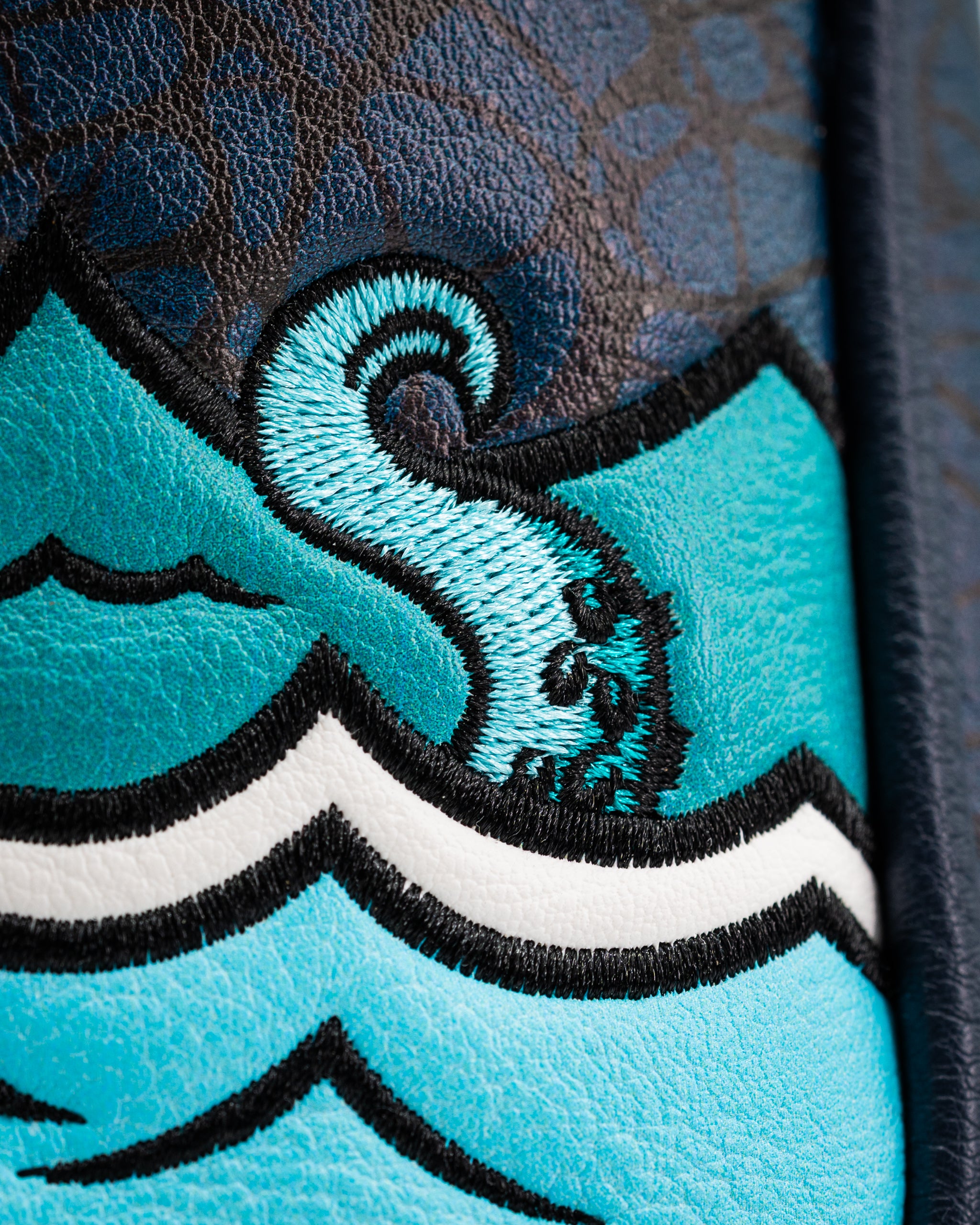 Close-up of the Kraken mallet putter cover featuring vibrant blue waves and intricate embroidered details.