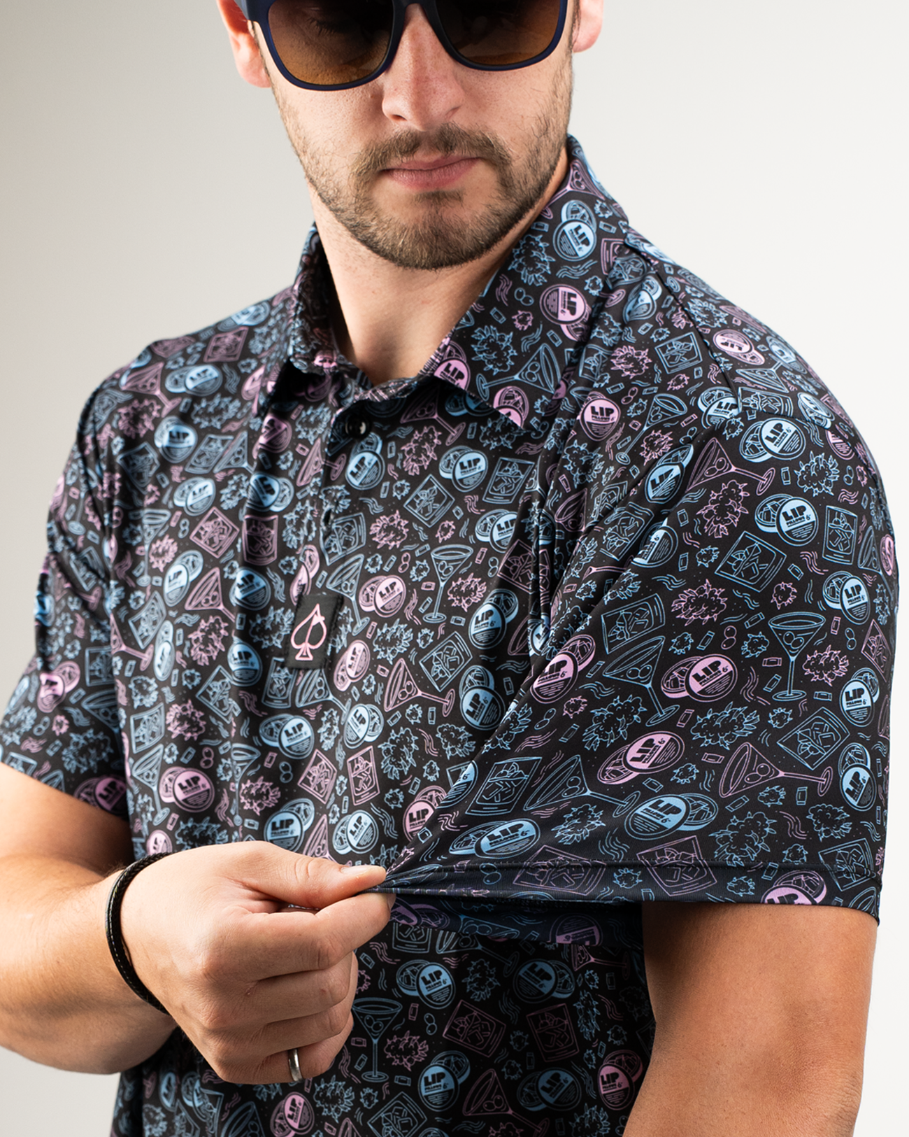 Bold golf shirt featuring a colorful pattern of lip pillows and playful designs, worn by a man adjusting the sleeve.