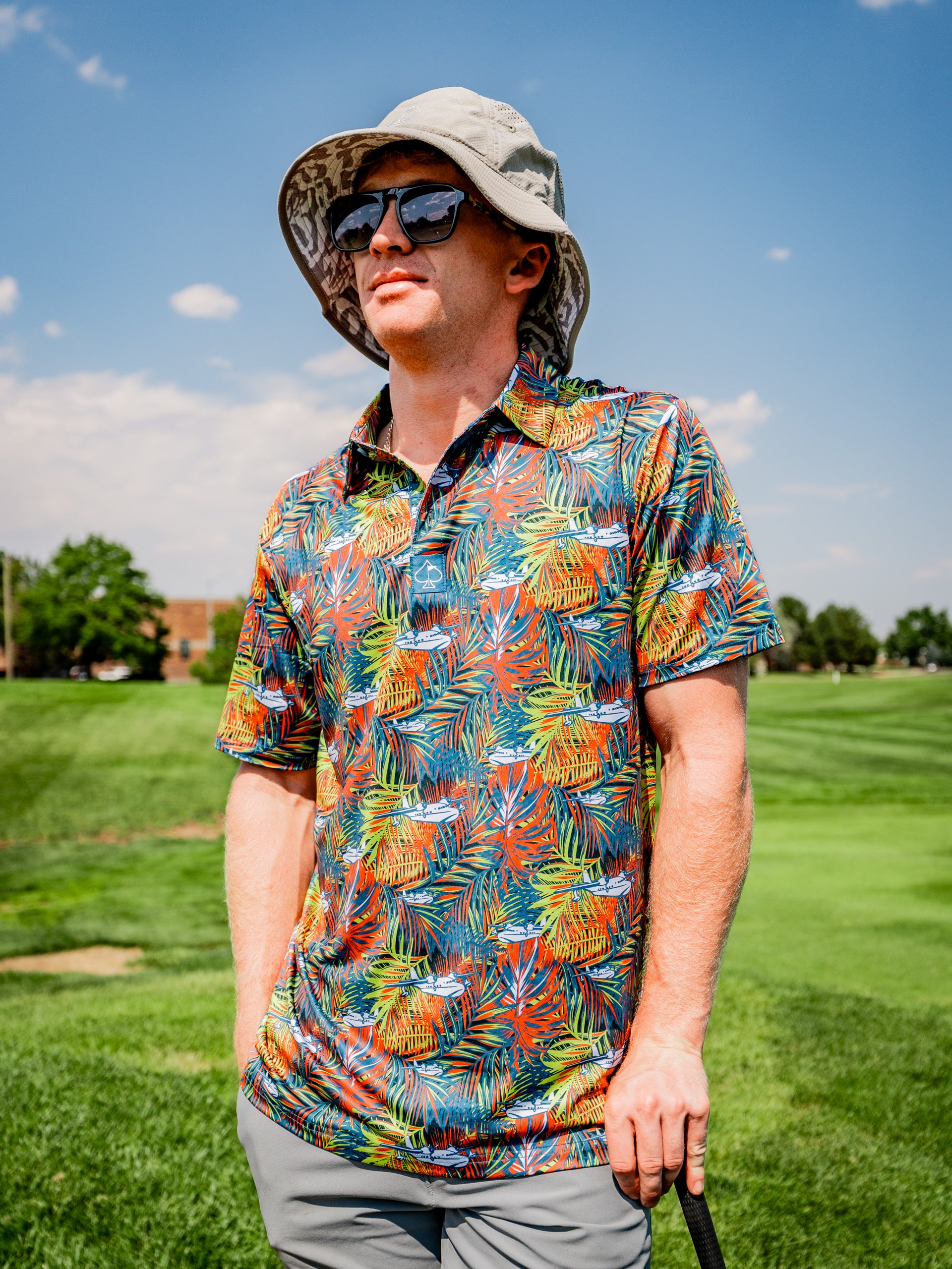 Man wearing a colorful Margaritaville Bama Breeze golf shirt and a wide-brimmed hat on a sunny golf course.