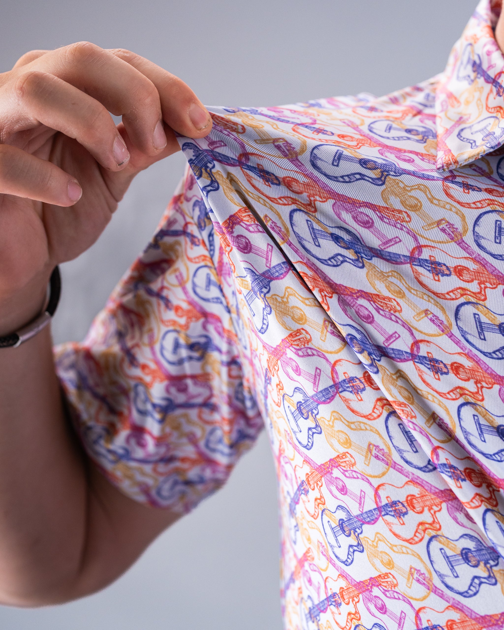 Close-up of a colorful, guitar pattern button-up shirt with puffy sleeves, perfect for bold golf apparel.