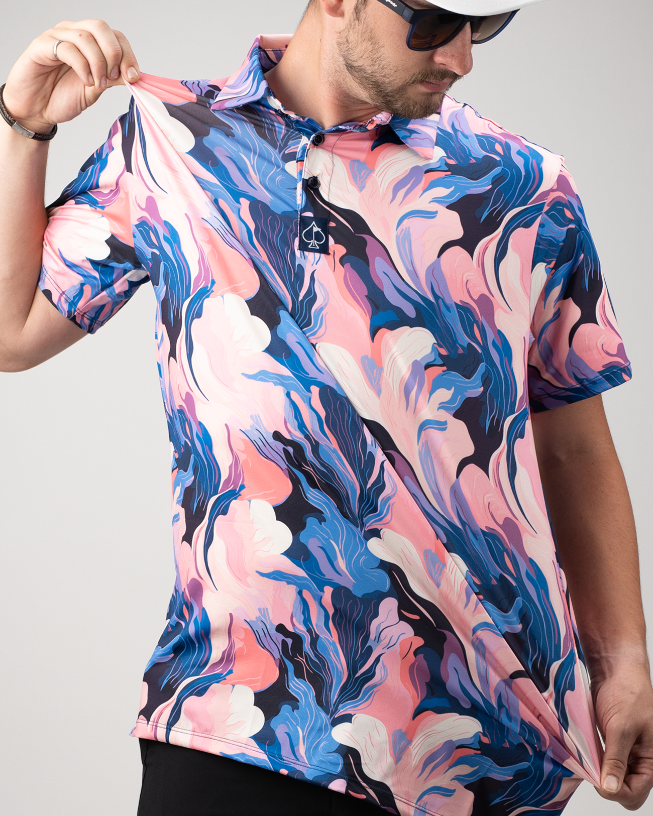 A golfer showcases a vibrant Melting Floral polo shirt featuring a bold pink and blue floral pattern.