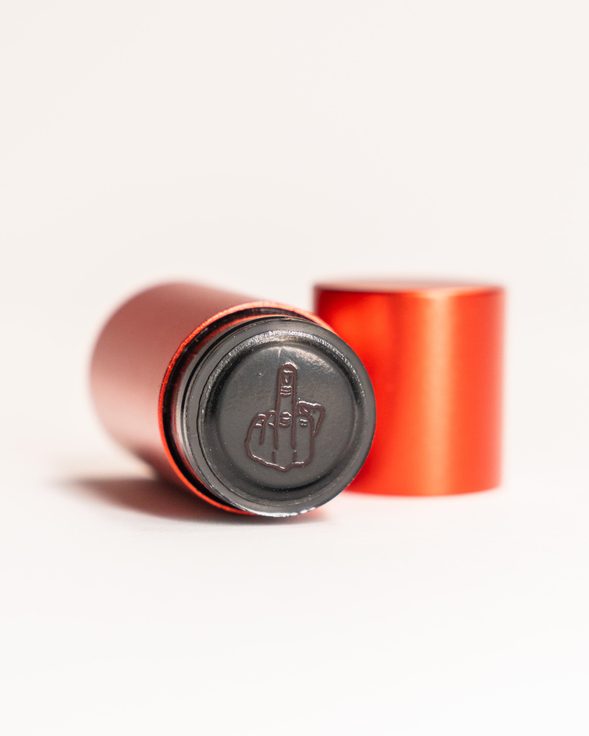 Red cylindrical stamp with a black bottom featuring an engraved middle finger gesture.
