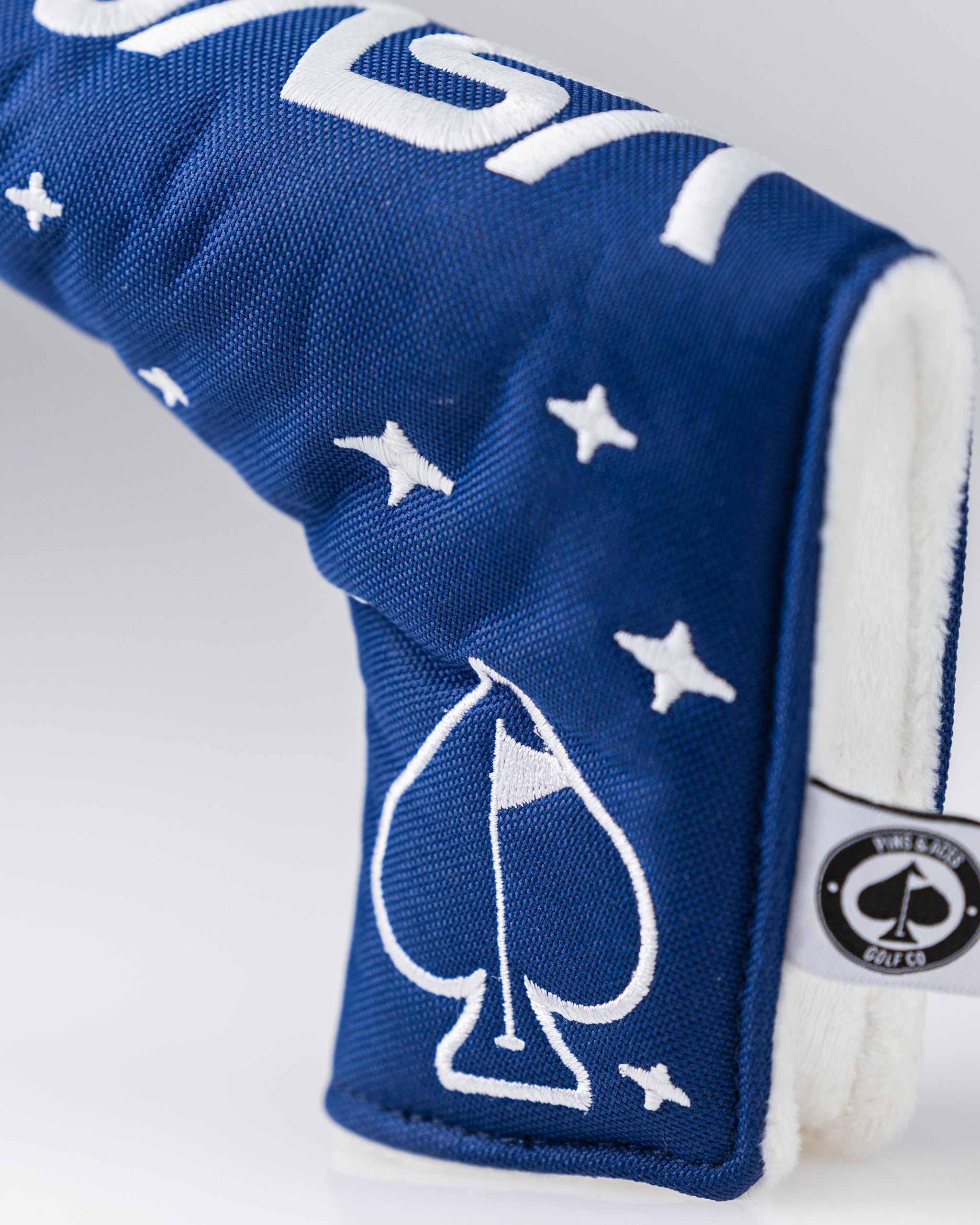 Bold blue golf headcover with white star and spade embroidery, featuring a white interior lining for standout course style.