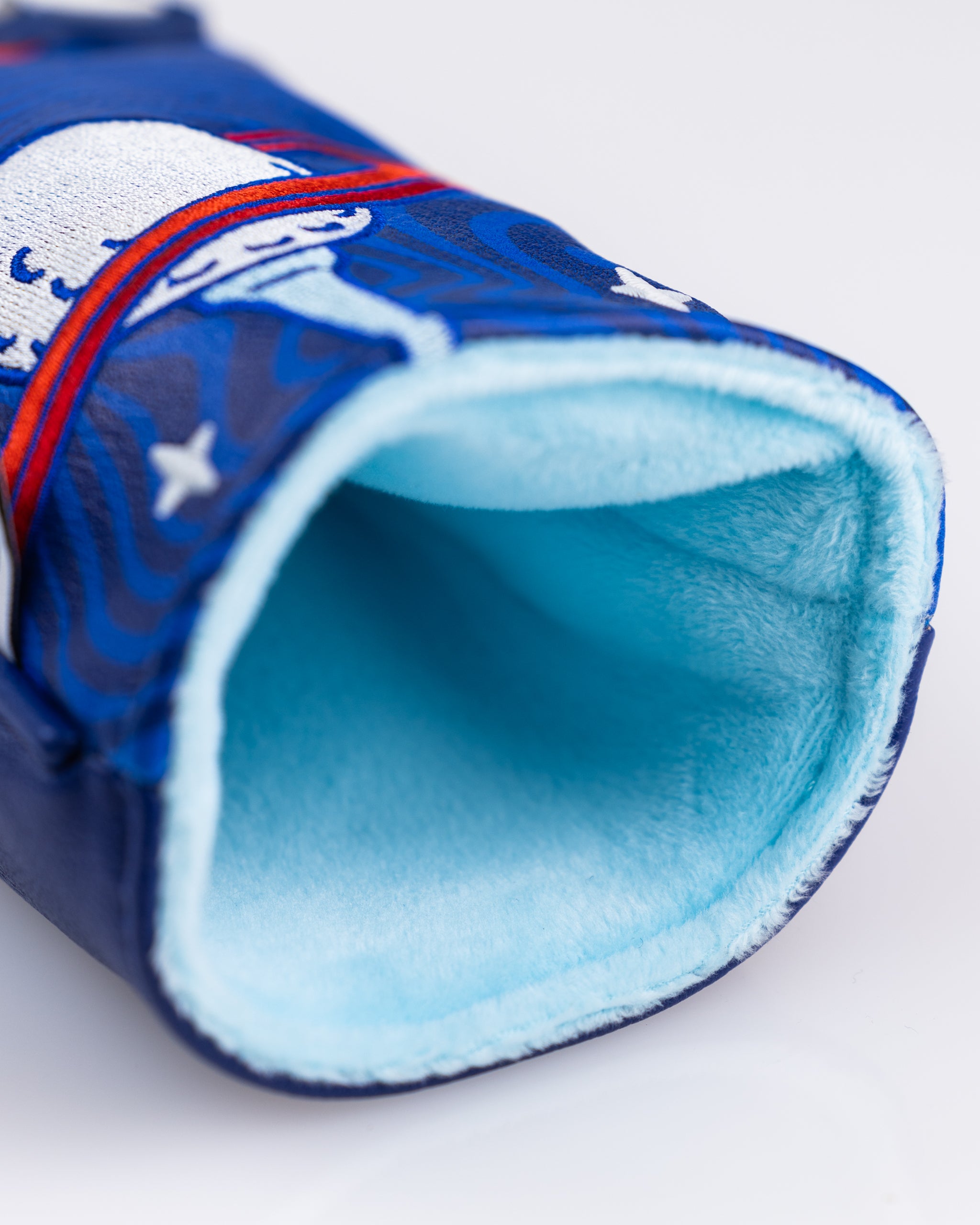 Close-up of a bold blue golf headcover with red, white, and blue embroidered details, lined with soft light blue fleece.