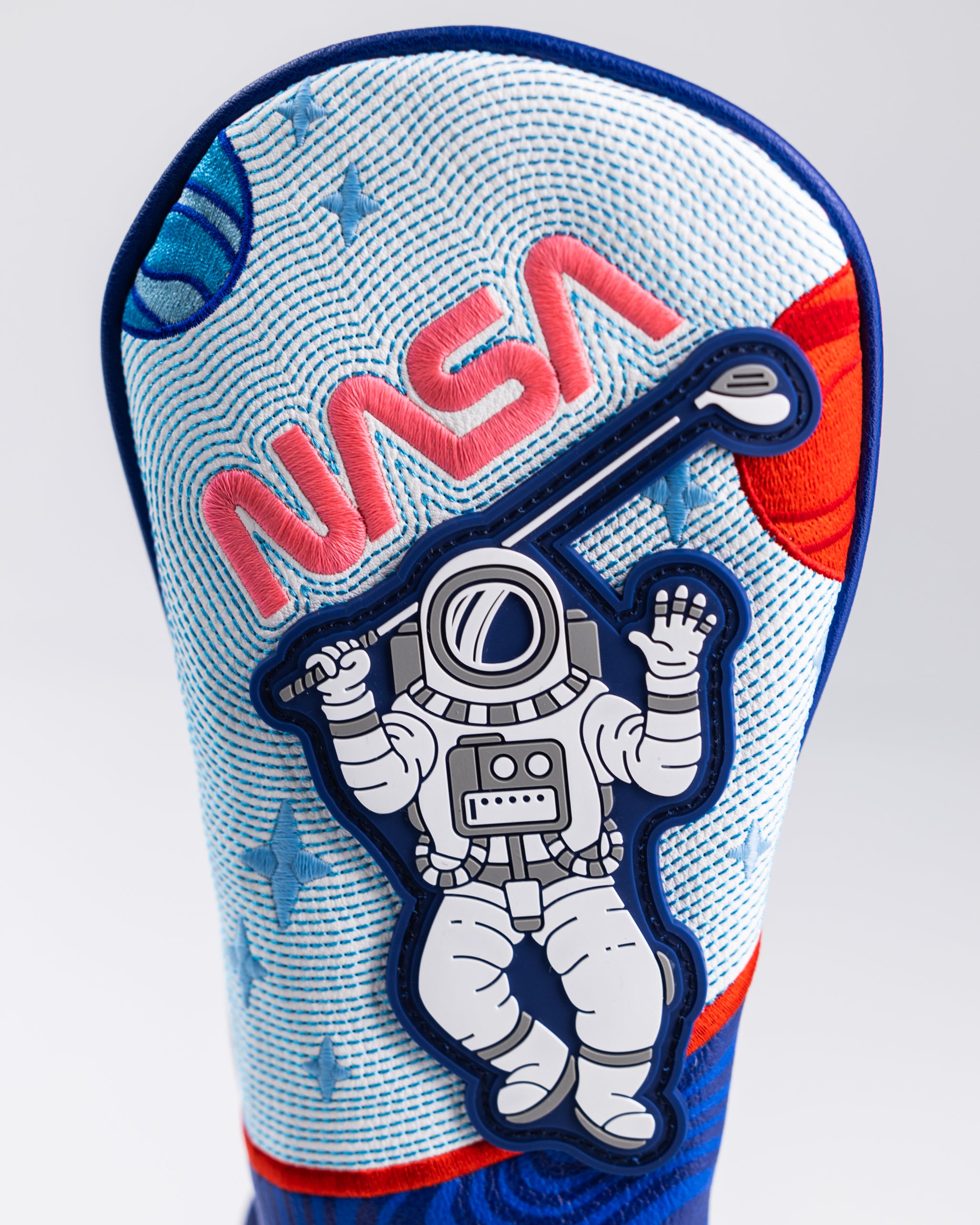 Colorful golf headcover with astronaut patch, "NASA" embroidery, space-themed design, and bold blue, red, and white accents.