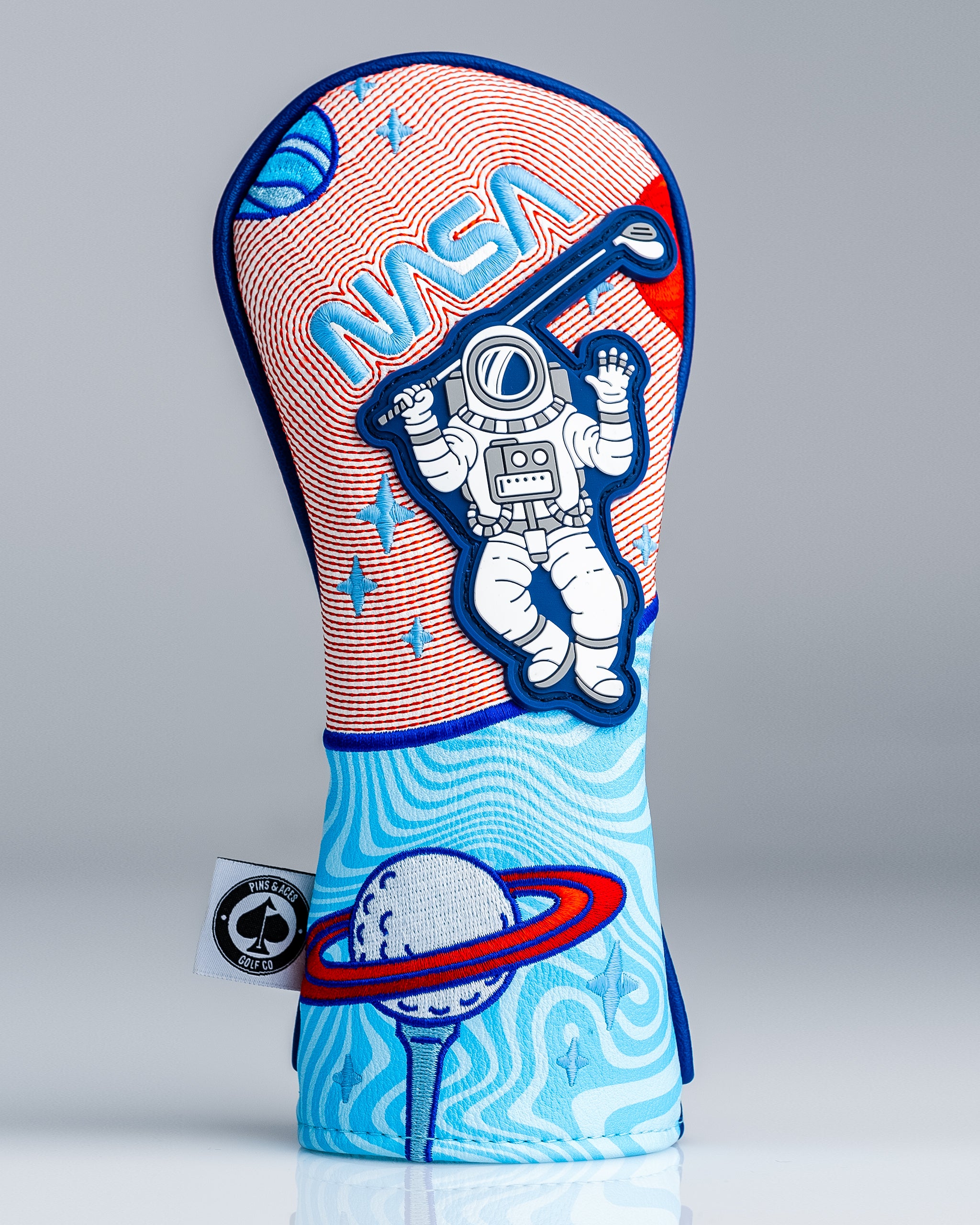 Colorful golf headcover with space-themed astronaut, planets, and stars in red, blue, and white, perfect for bold golf style.
