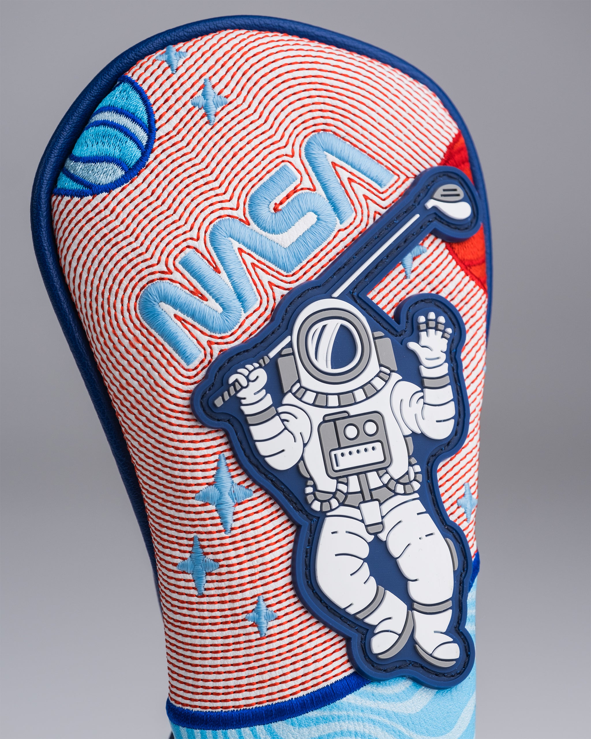 Colorful golf club headcover with astronaut patch, red, blue, and white space-themed embroidery, perfect for bold golf app...
