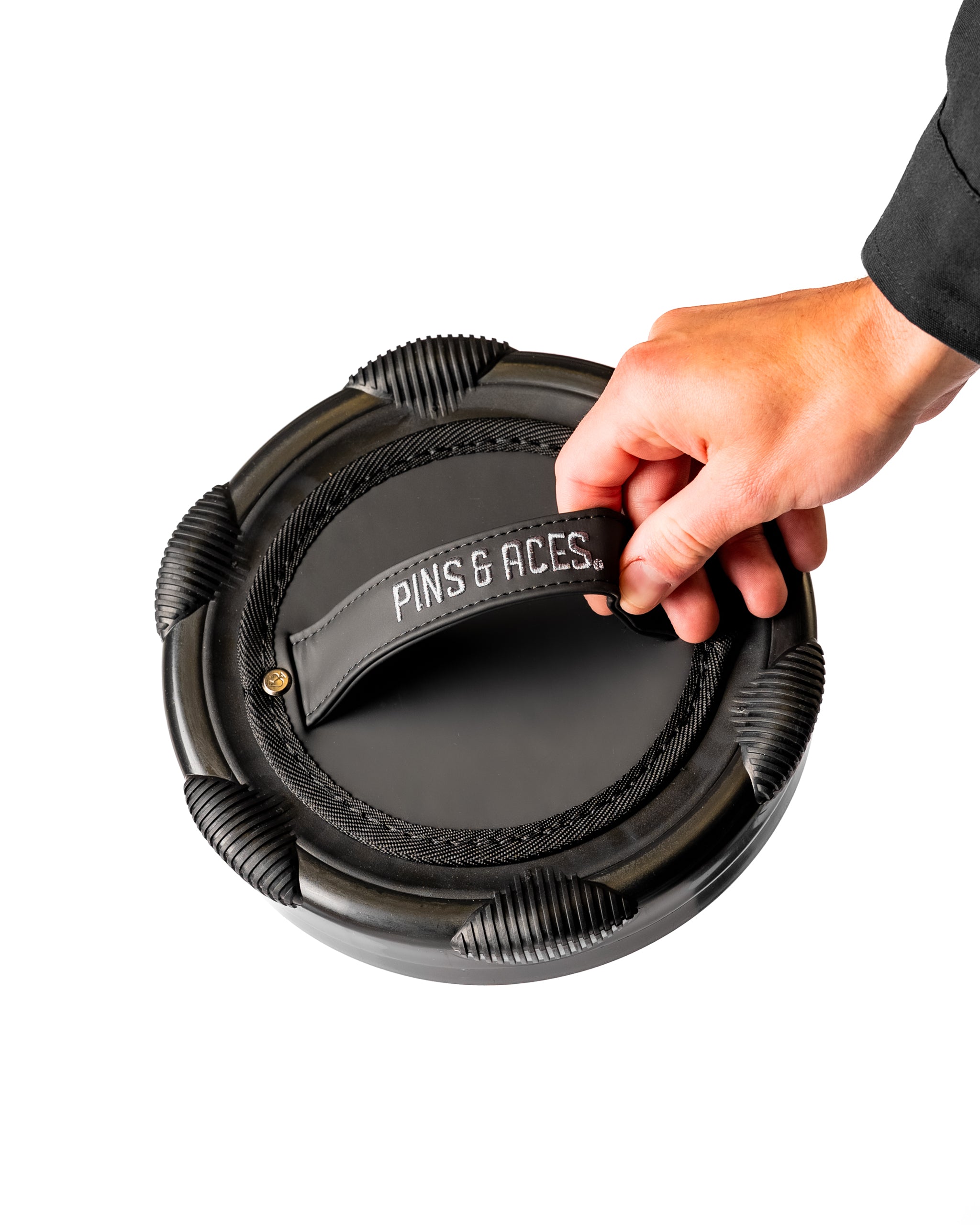 Den Caddy in Obsidian color, featuring a textured grip and a hand reaching for the branded leather handle.