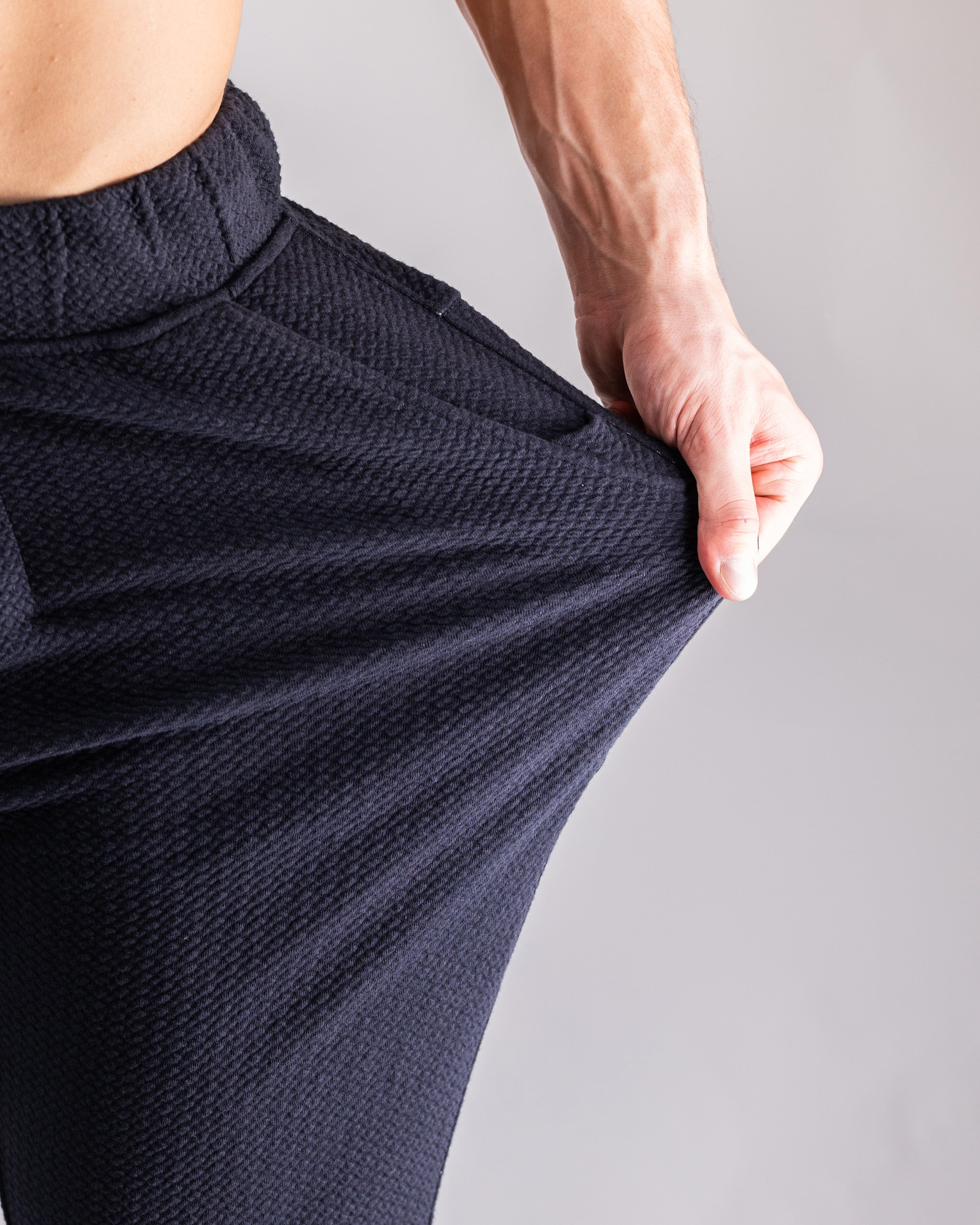 Close-up of black textured golf pants with a stretchy fit, highlighting bold, unique style for standout golfers.