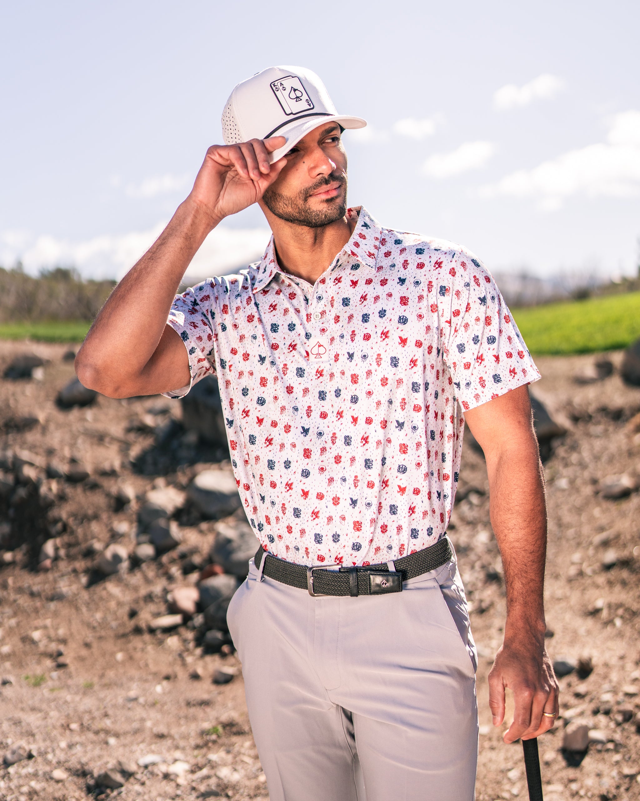 A golfer wearing an American Traditional polo with a colorful pattern, standing confidently on a course with a golf club.
