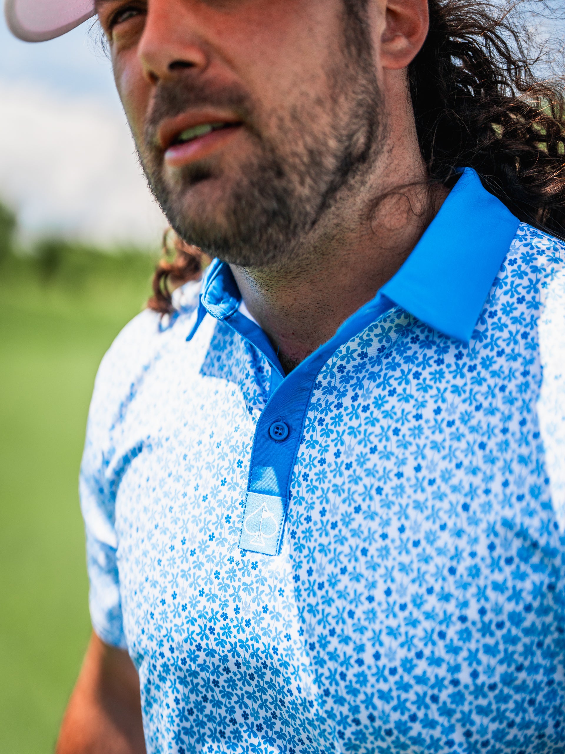 Man wearing a blue floral golf polo shirt on the course, showcasing a stylish and vibrant design perfect for golfers.