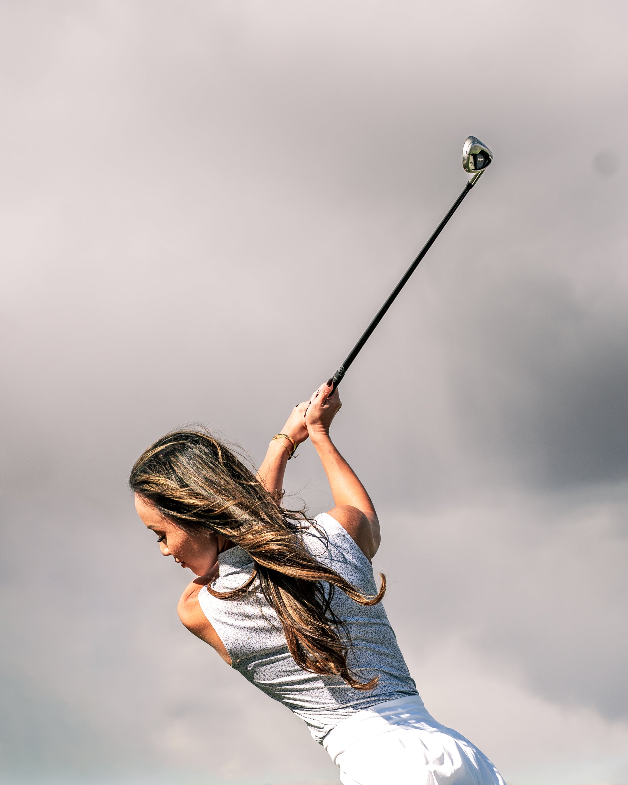 A woman swings a golf club on the course, showcasing the Women's Best Friend Light golf apparel.