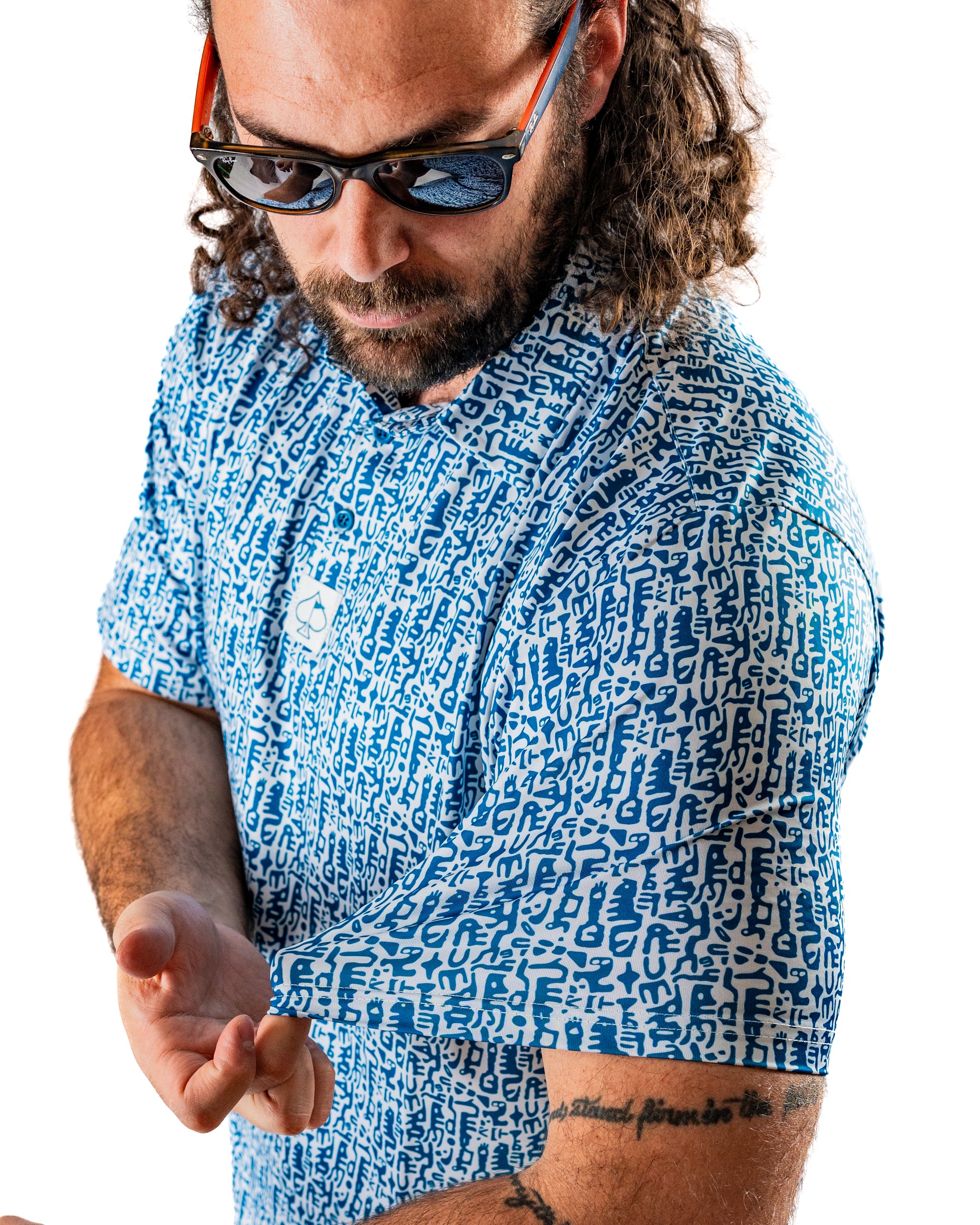 Bold blue Maze Craze golf shirt featuring a unique pattern, worn by a man adjusting his sleeve while wearing sunglasses.
