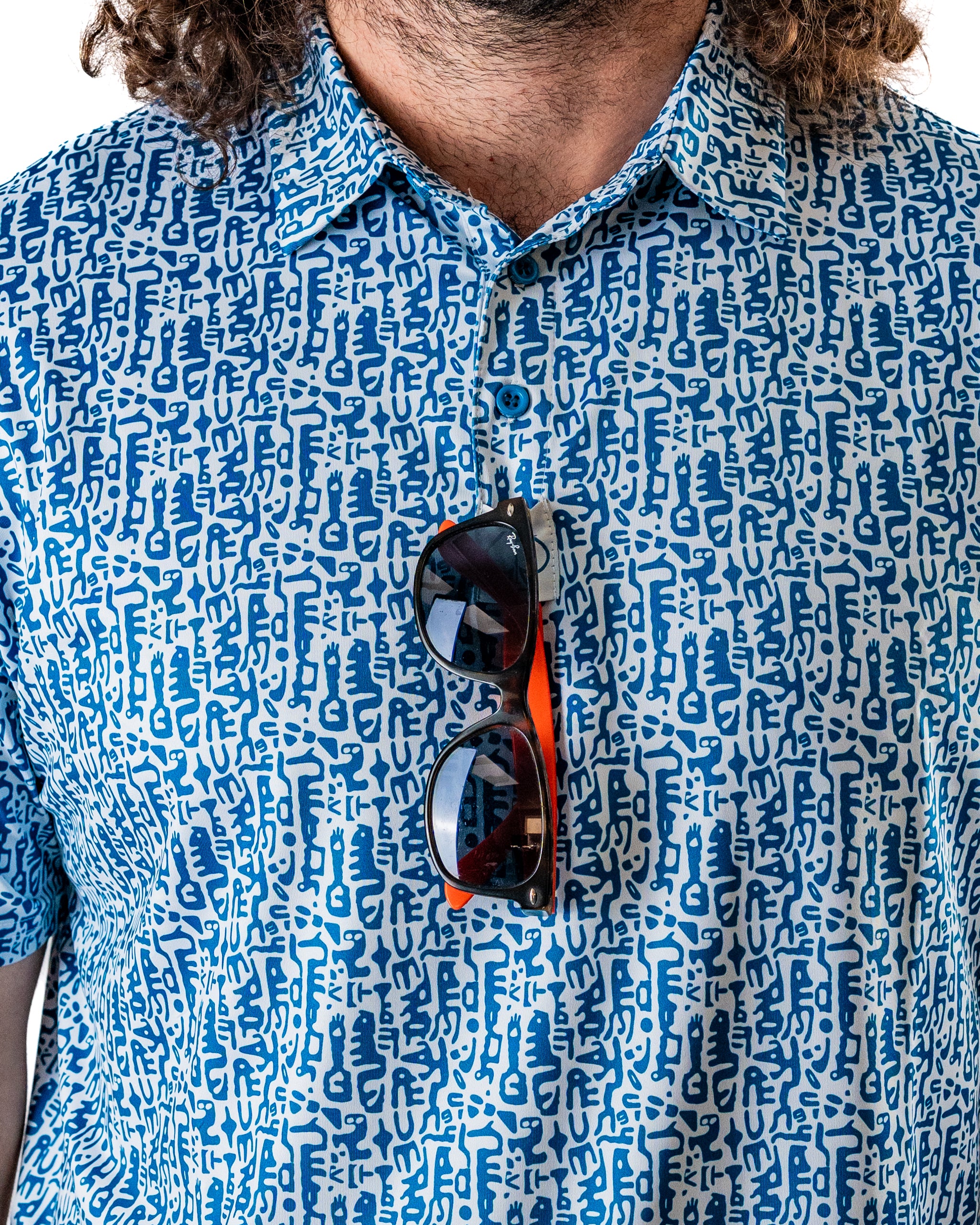 Bold blue Maze Craze golf shirt featuring a unique pattern, with sunglasses resting on the chest area.