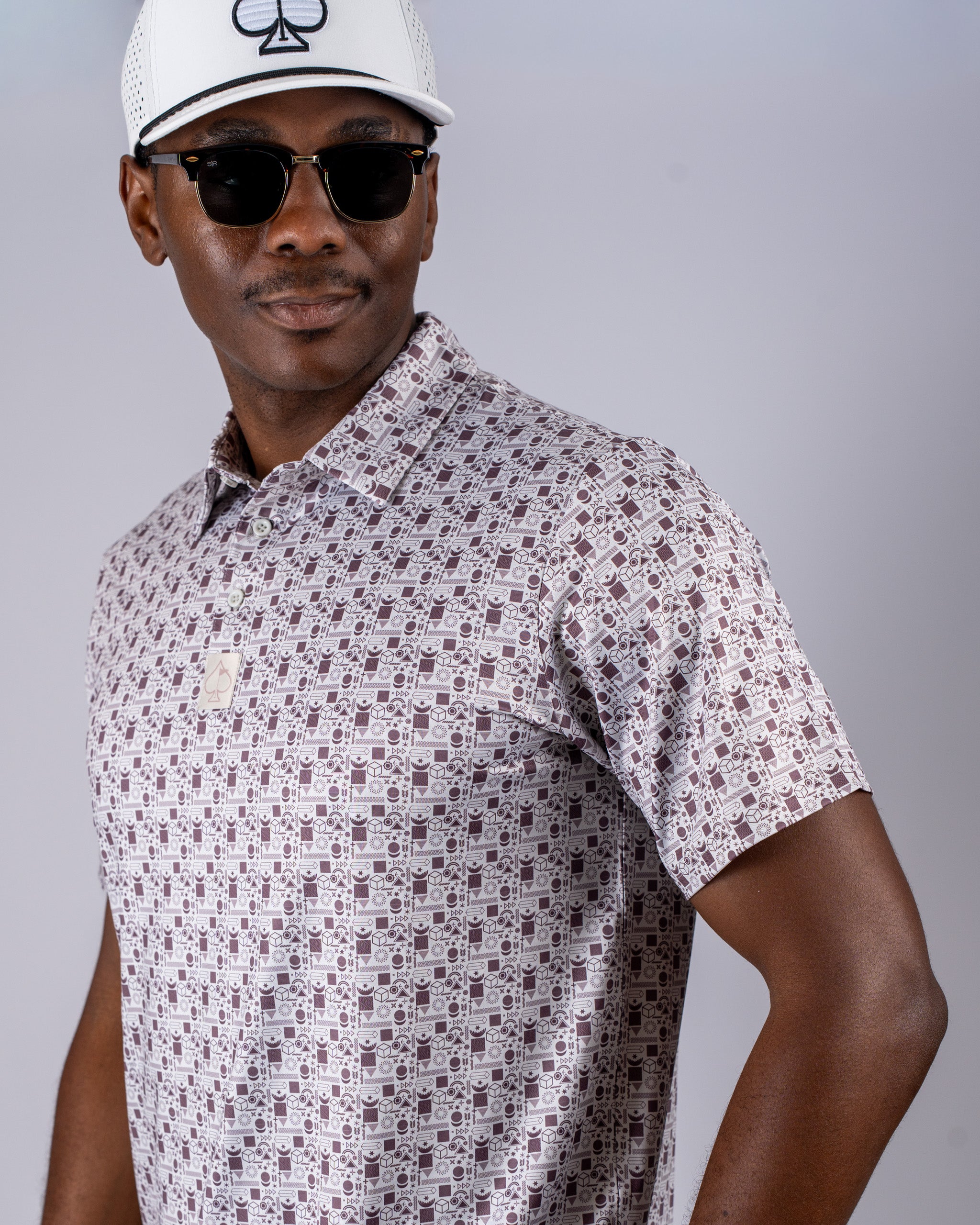 Stylish golfer wearing a retro patterned polo shirt and sunglasses, showcasing bold golf fashion.