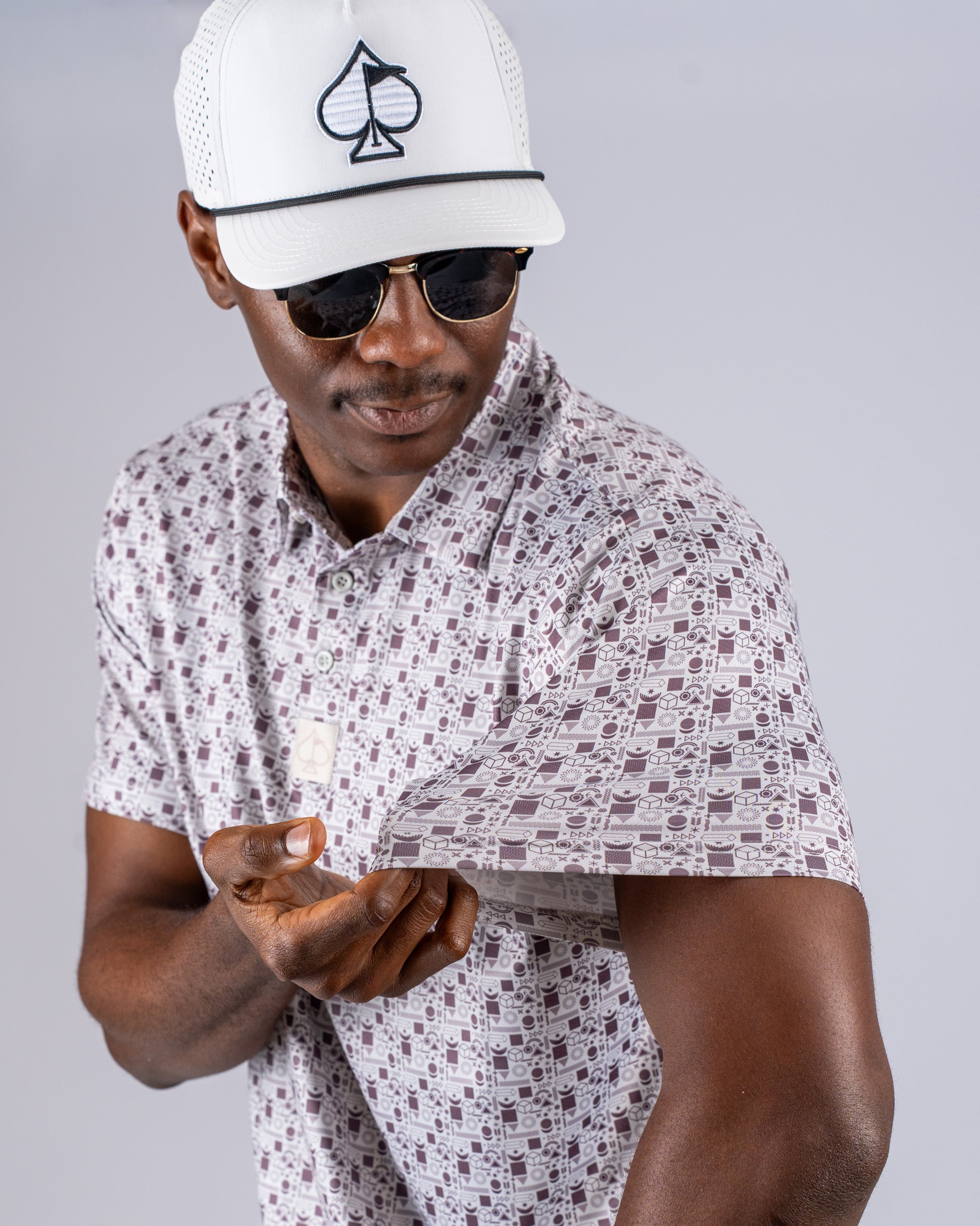 A man wearing a retro-patterned golf shirt and a stylish cap, showcasing the shirt's unique sleeve design.