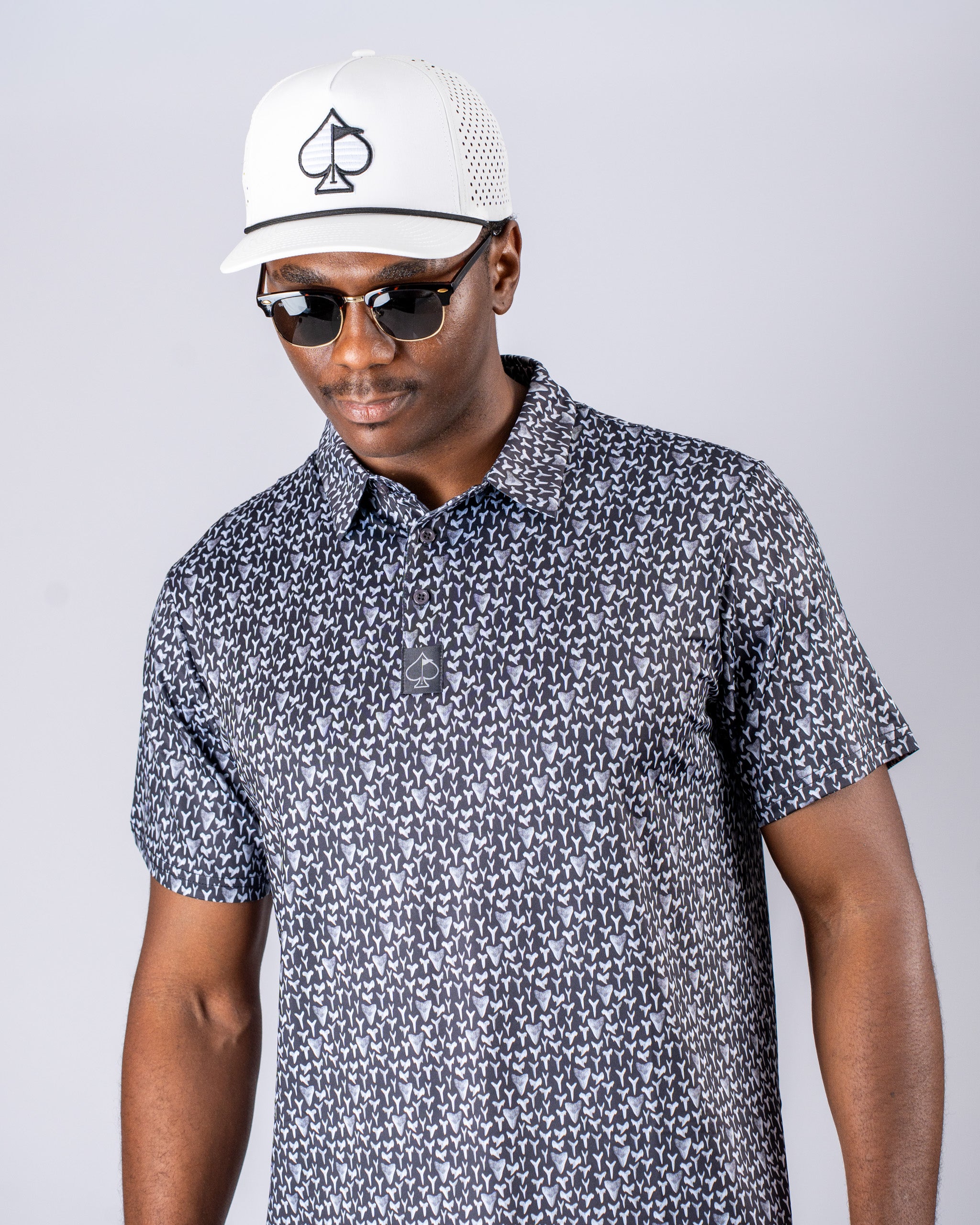 Stylish golfer wearing a patterned shirt and a white cap with a logo, showcasing a confident look on the course.