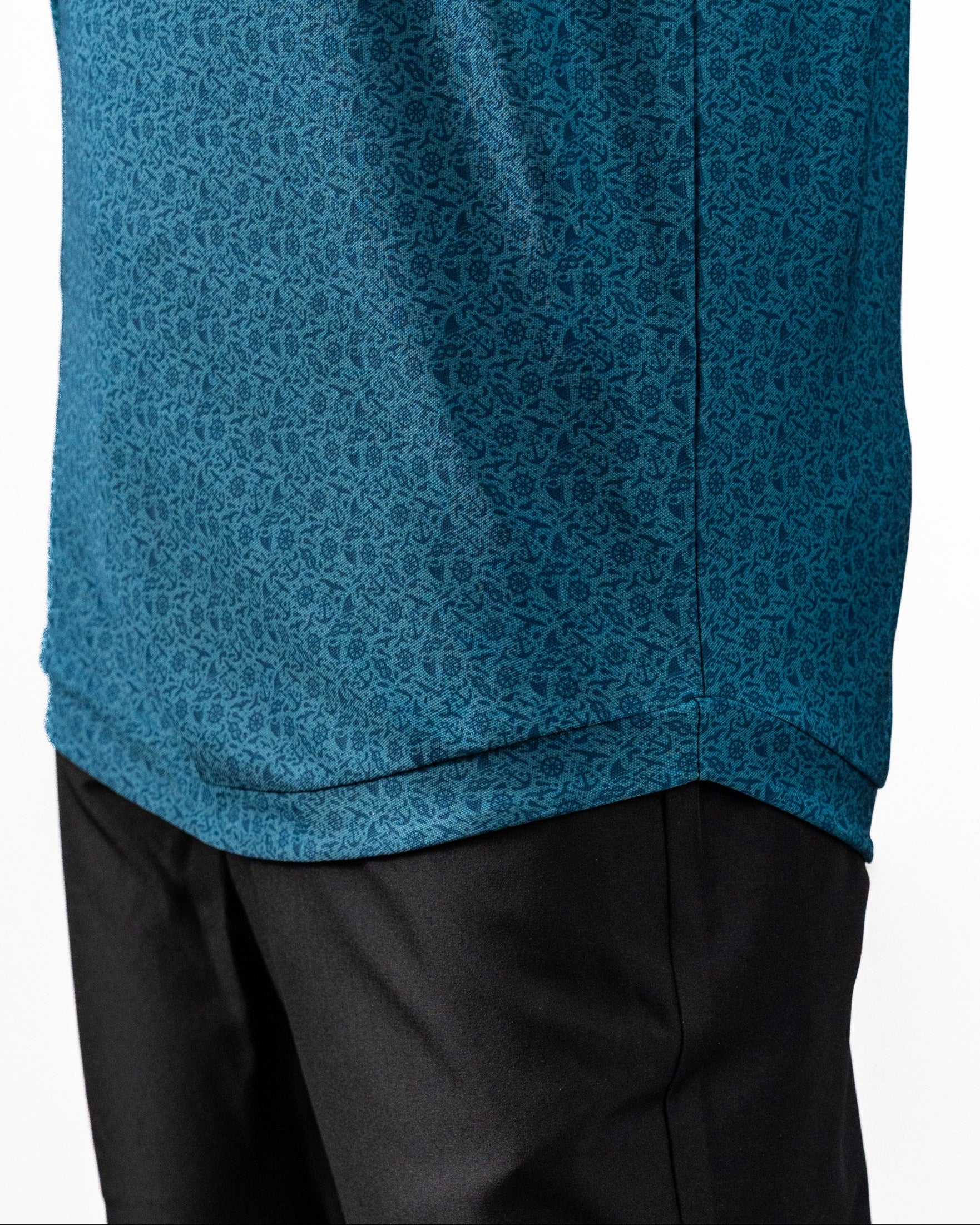 Close-up of a teal Player Preferred™ Polo shirt with a subtle, intricate pattern, paired with black pants.