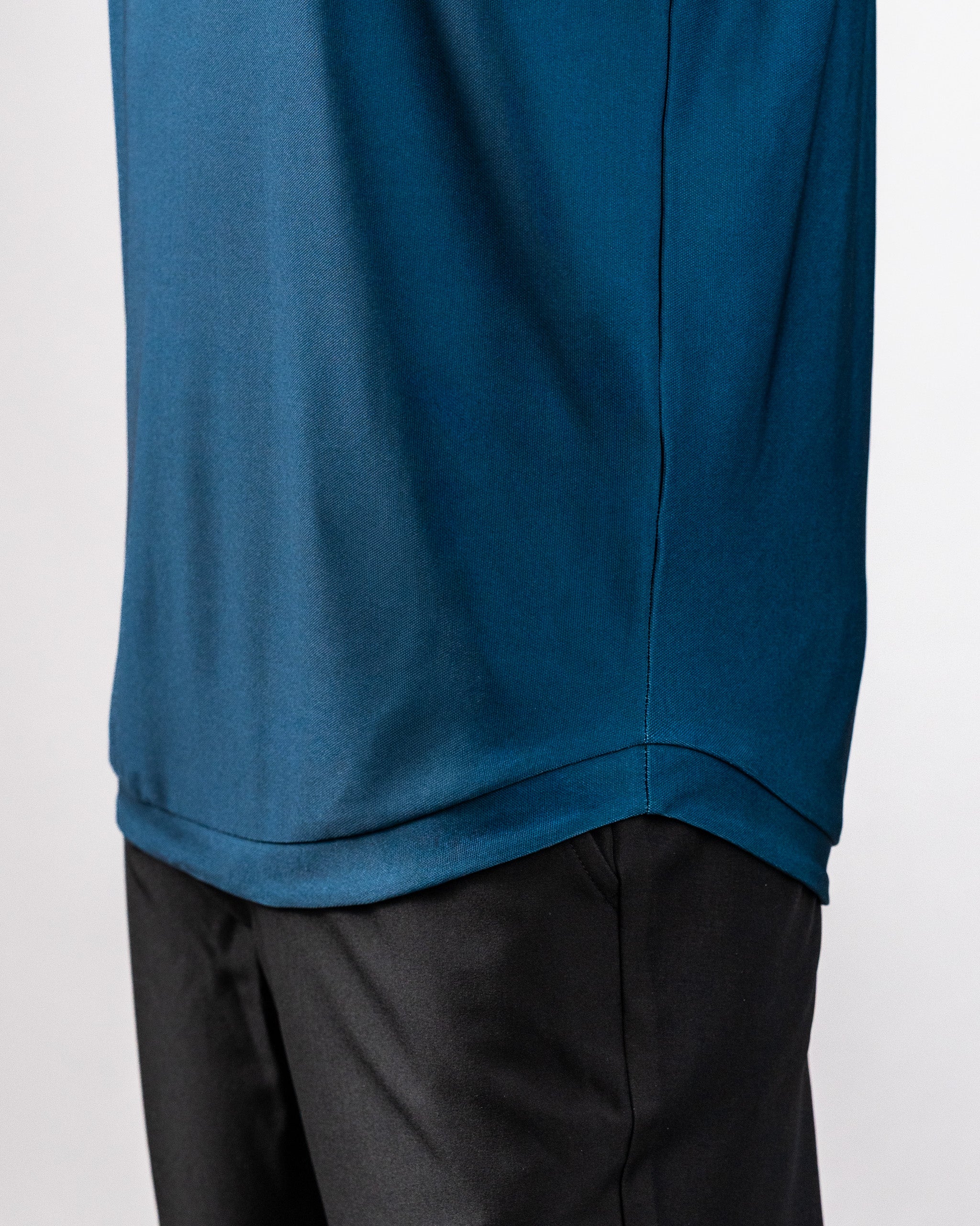 Close-up of a navy Player Preferred™ Polo with Spade Fade design, worn over black pants, showing fabric texture and stitching.