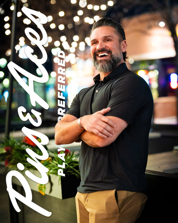 Man smiling outdoors at night, wearing a black golf polo, with bold white text overlay reading "Rise & Shine, Play Perfect."