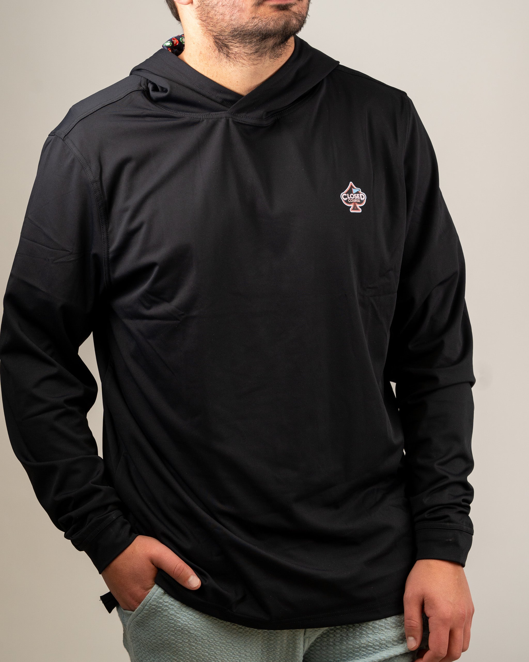 Men's black performance golf hoodie featuring a closed course logo, designed for comfort and style on the golf course.