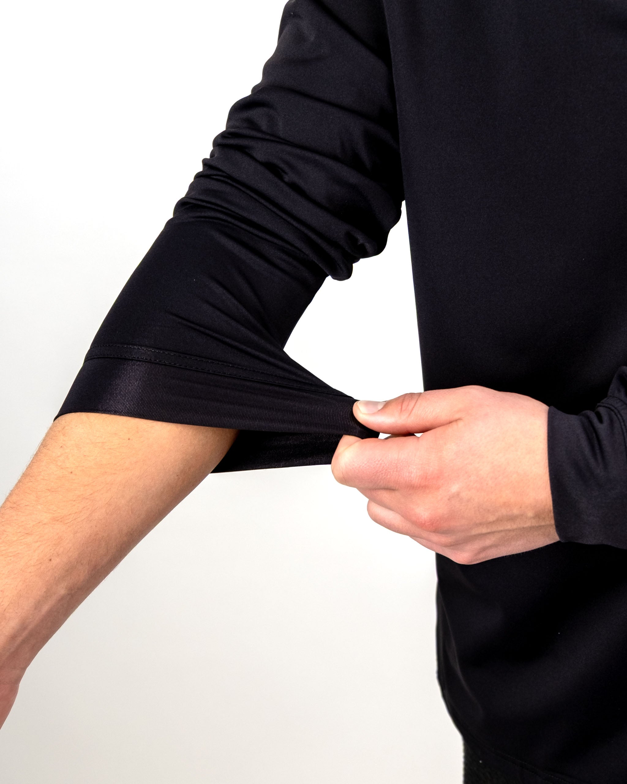 Close-up of a person pulling the sleeve of a black performance golf hoodie, showcasing its stretchable fabric and fit.