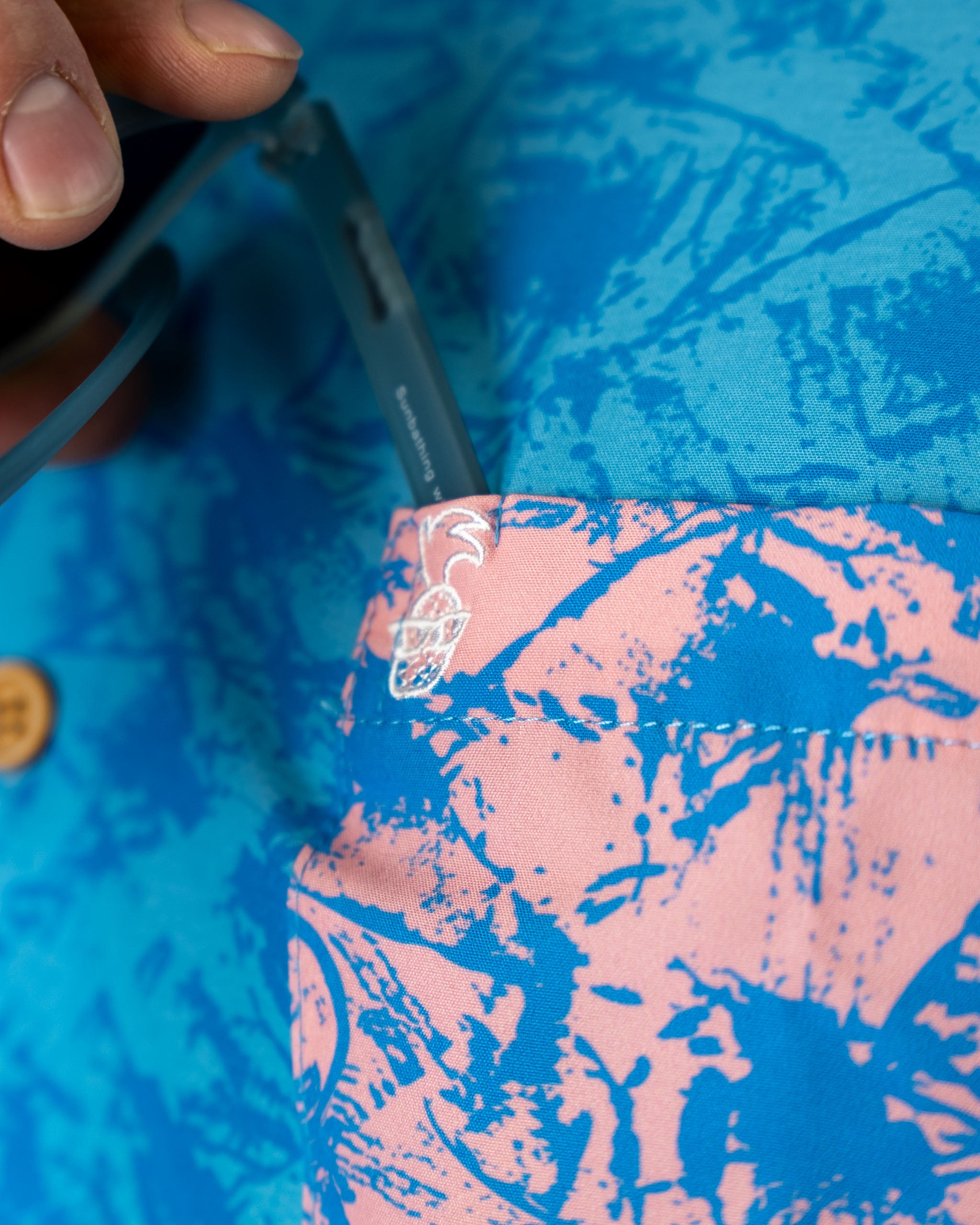 Pastel Drift Piña Boys shirt featuring a vibrant blue and pink design with a pocket for sunglasses.